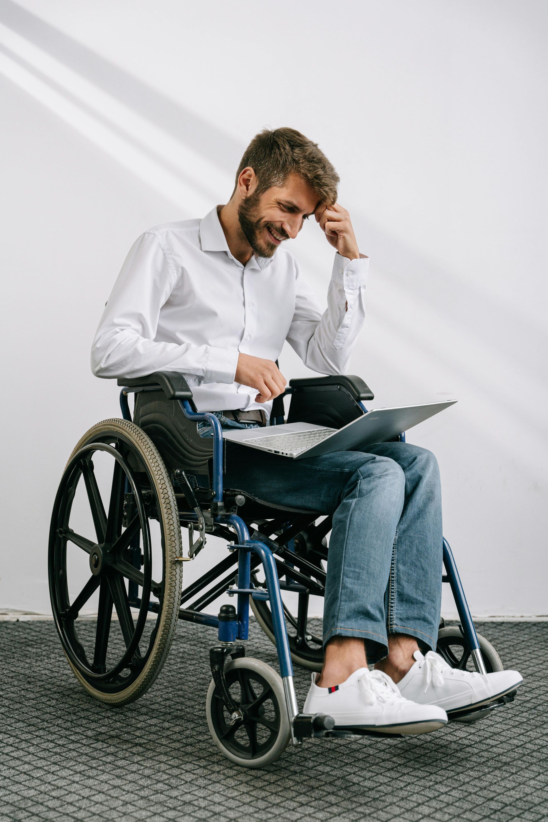 A man in a wheelchair is using a laptop computer.