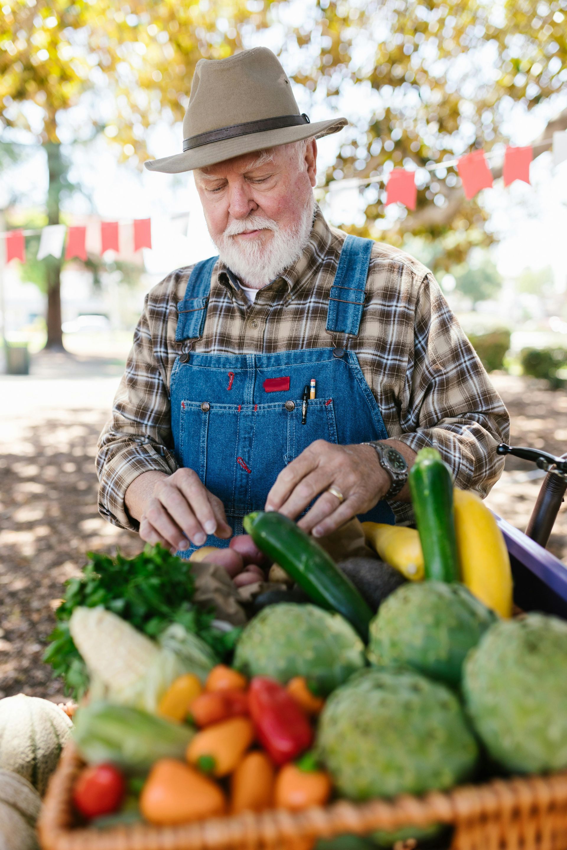 An older man is standing in front of a basket of vegetables.