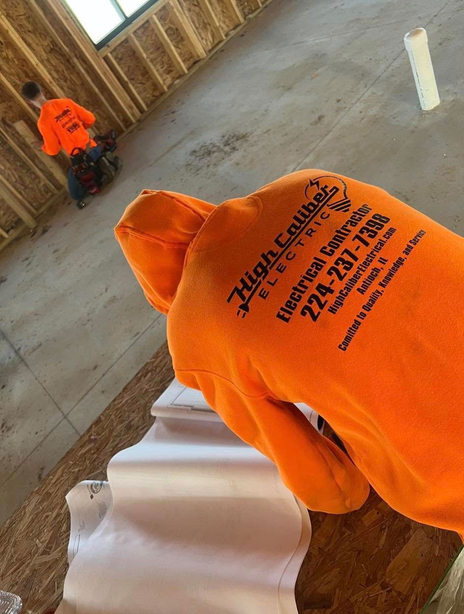 A person wearing an orange high caliber electrical sweatshirt