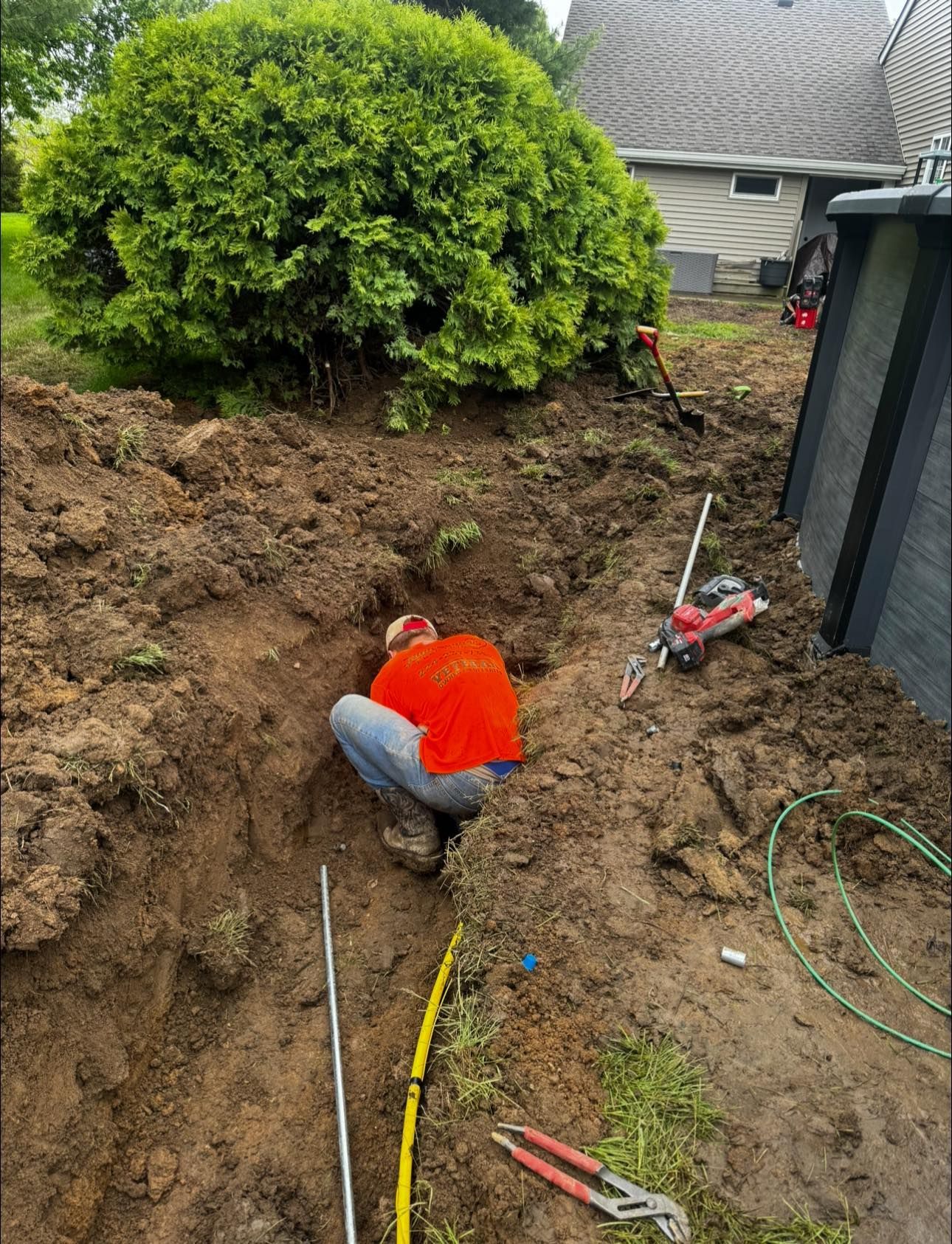A man is kneeling in the dirt next to a pool.