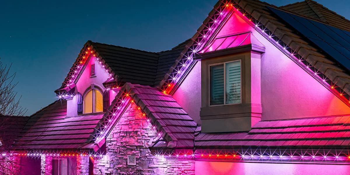 A house is decorated with pink and red christmas lights.