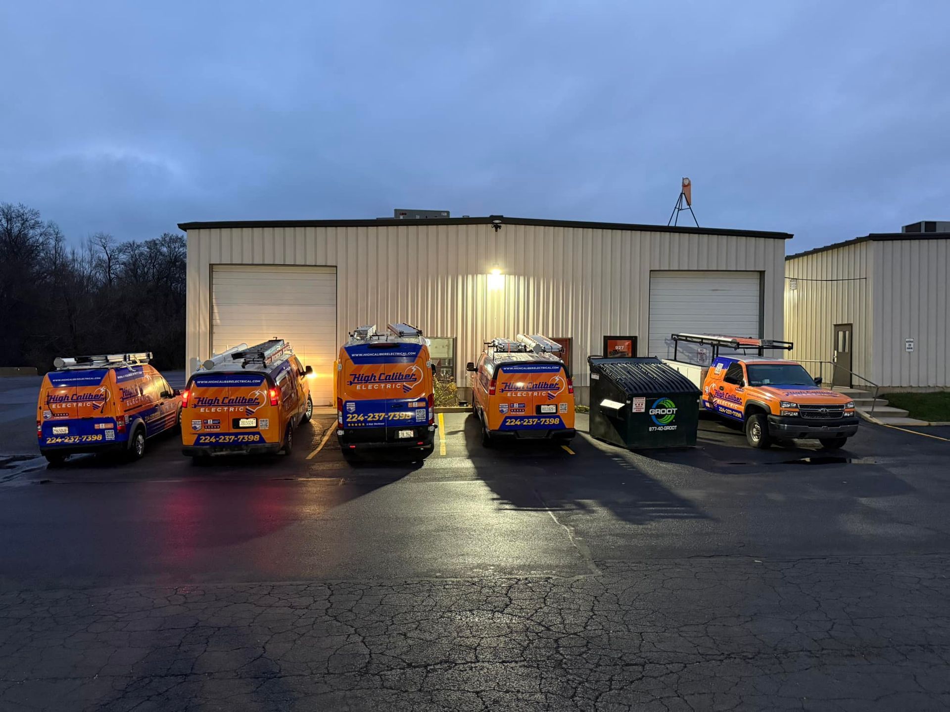 A row of orange and blue trucks are parked in front of a building.