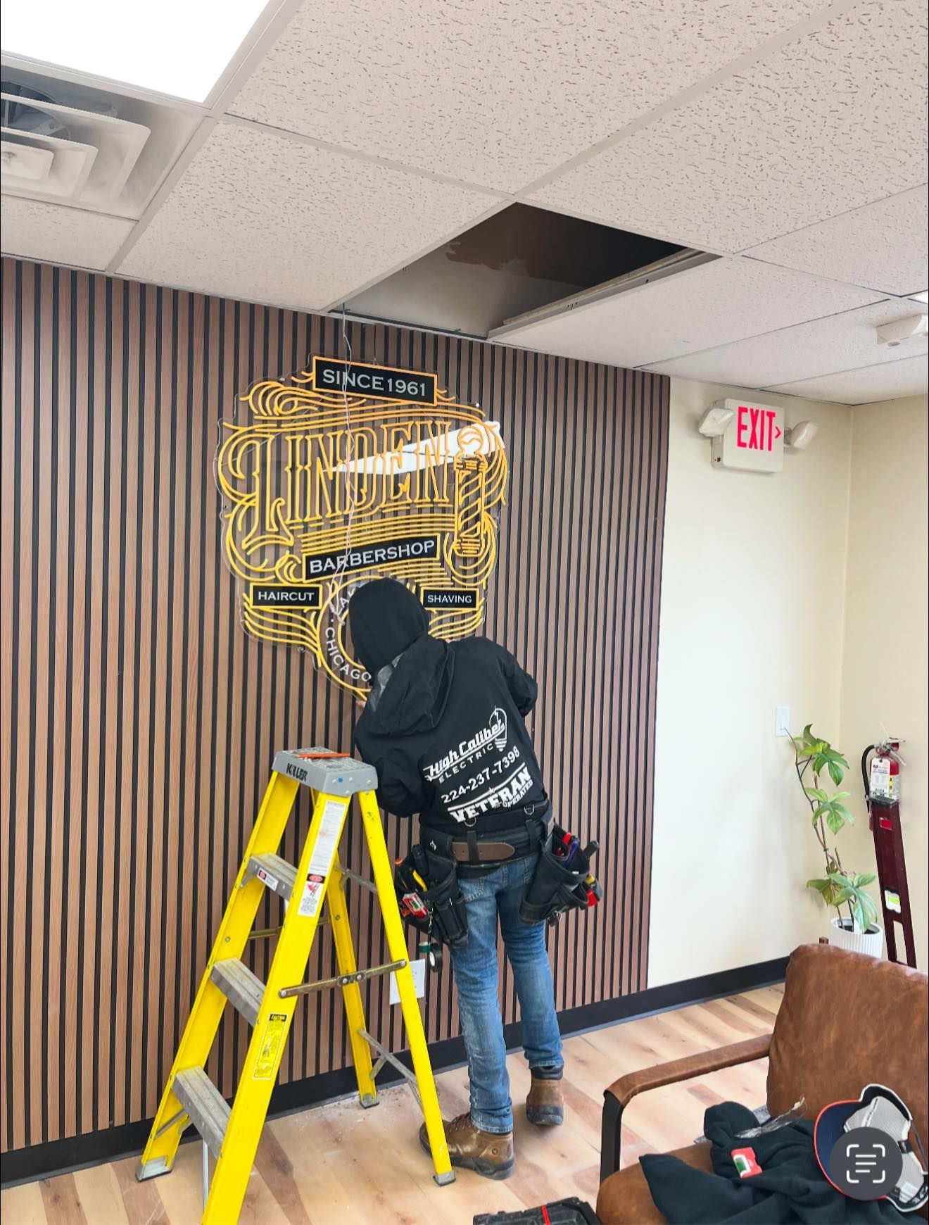 A man is standing on a ladder in front of a wall with a police badge on it.