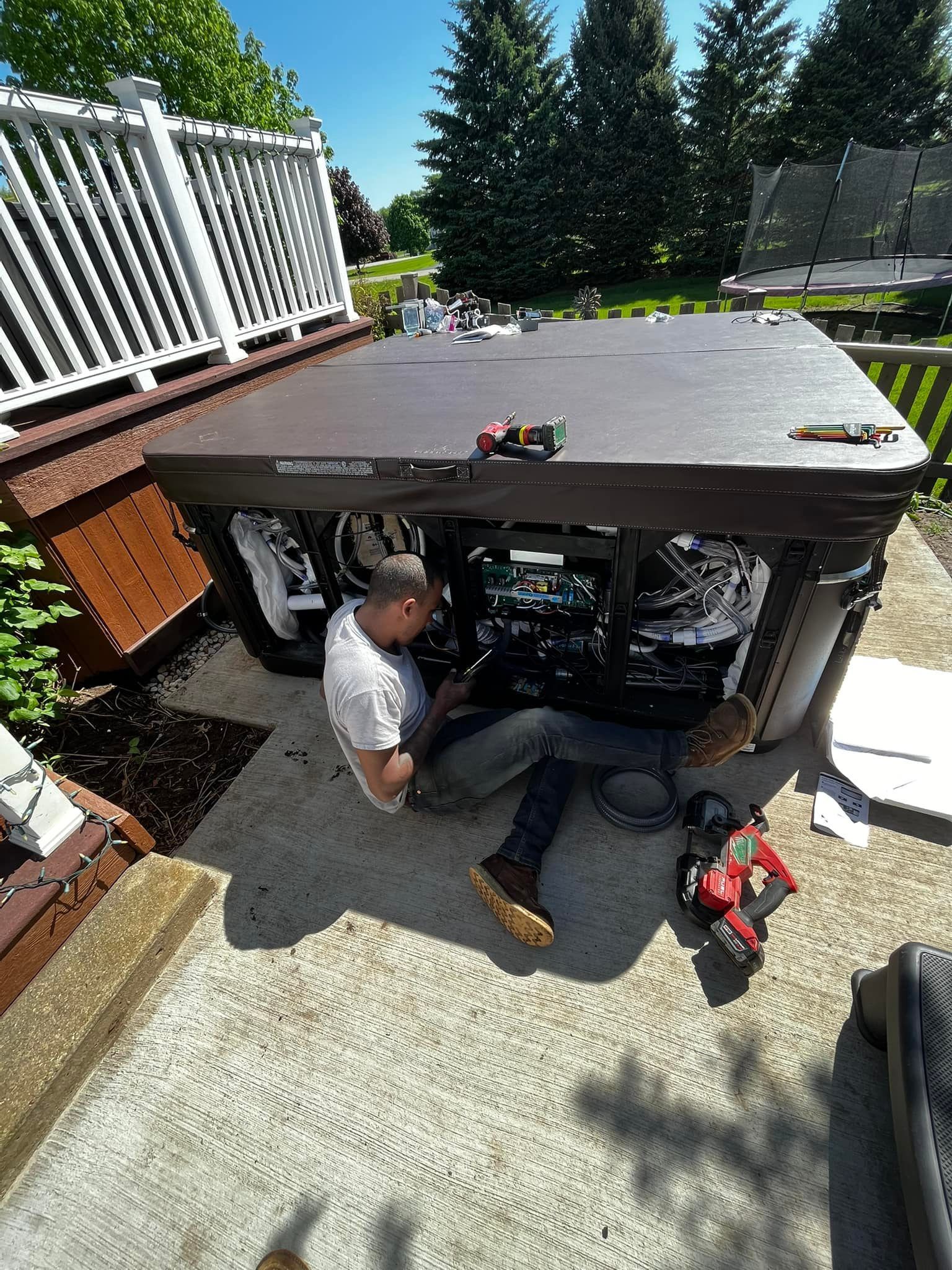 A man is sitting on the ground working on a hot tub.