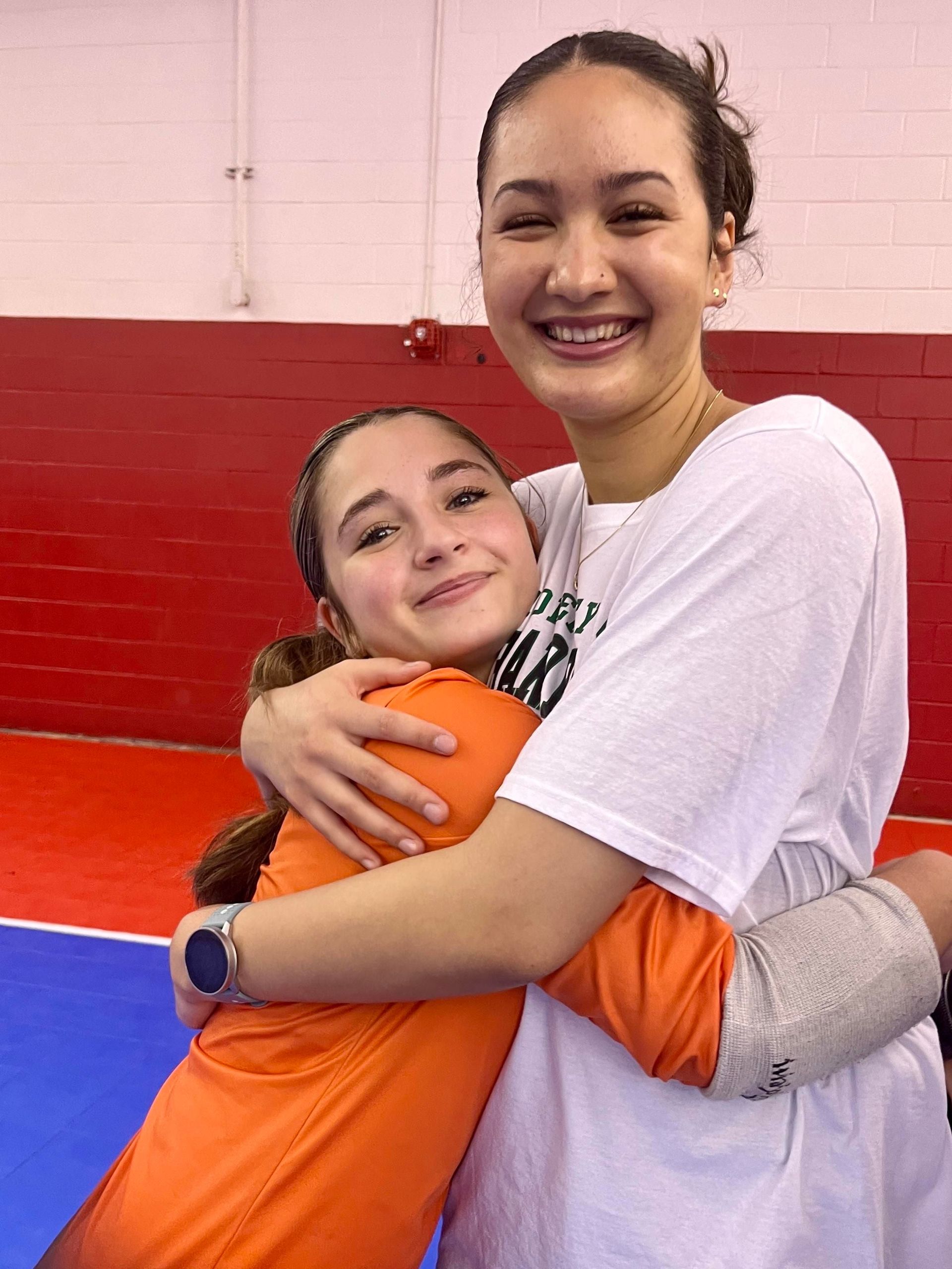 Two young women are hugging each other in a gym.
