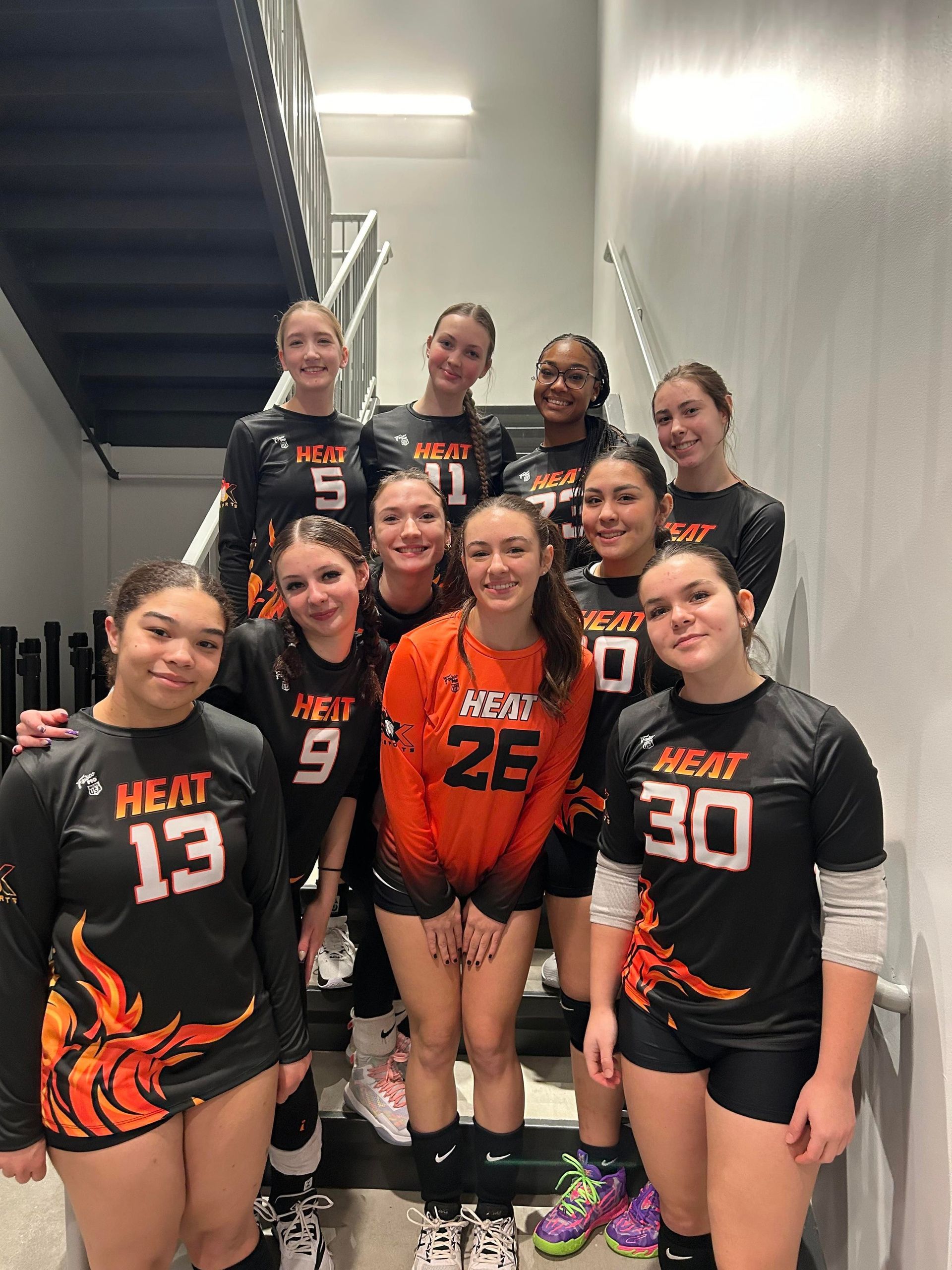 A group of volleyball players are posing for a picture in a locker room.