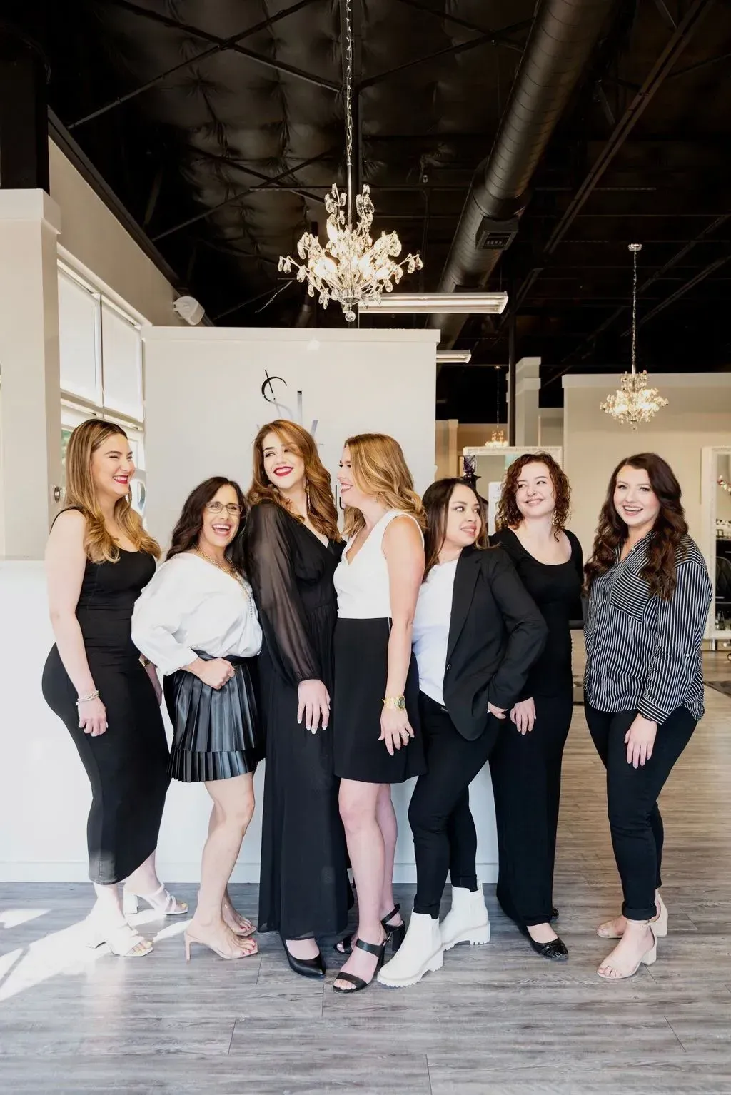 Part of slide show with laughing team of hairstylists surrounding Kristina Bynum, owner of Salon Le Volume.