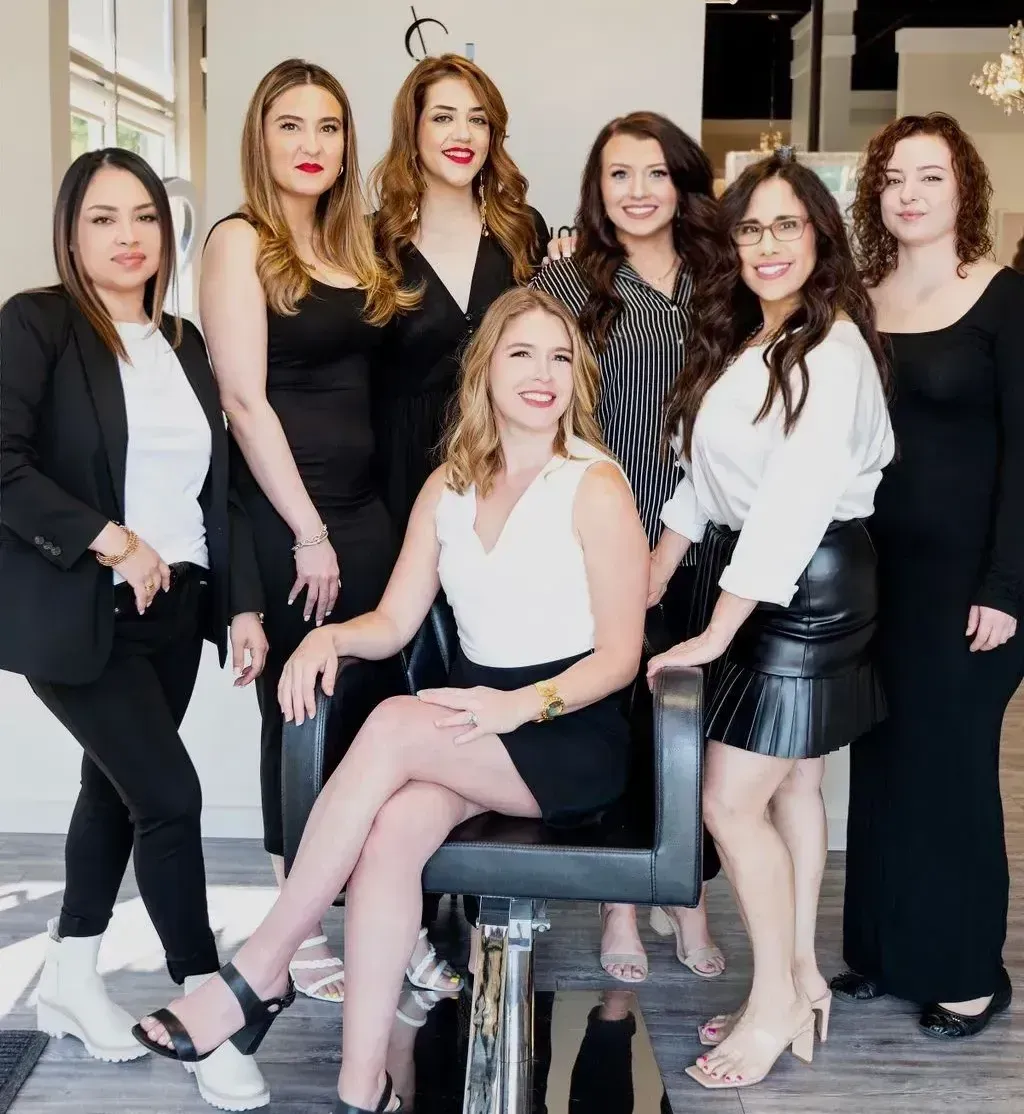 Frisco Texas based licensed hairstylists pose for group photo standing around Salon Le Volume owner Kristina Bynum (middle).