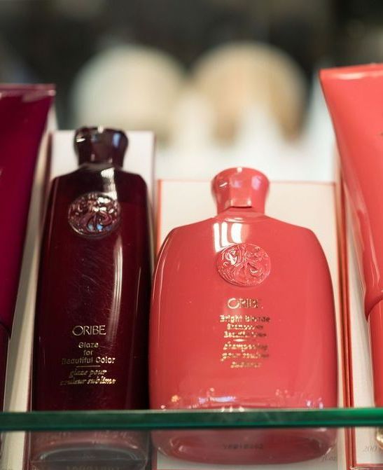 Close-up of orange-red Oribe shampoo bottle next to a brown Oribe conditioning glaze.