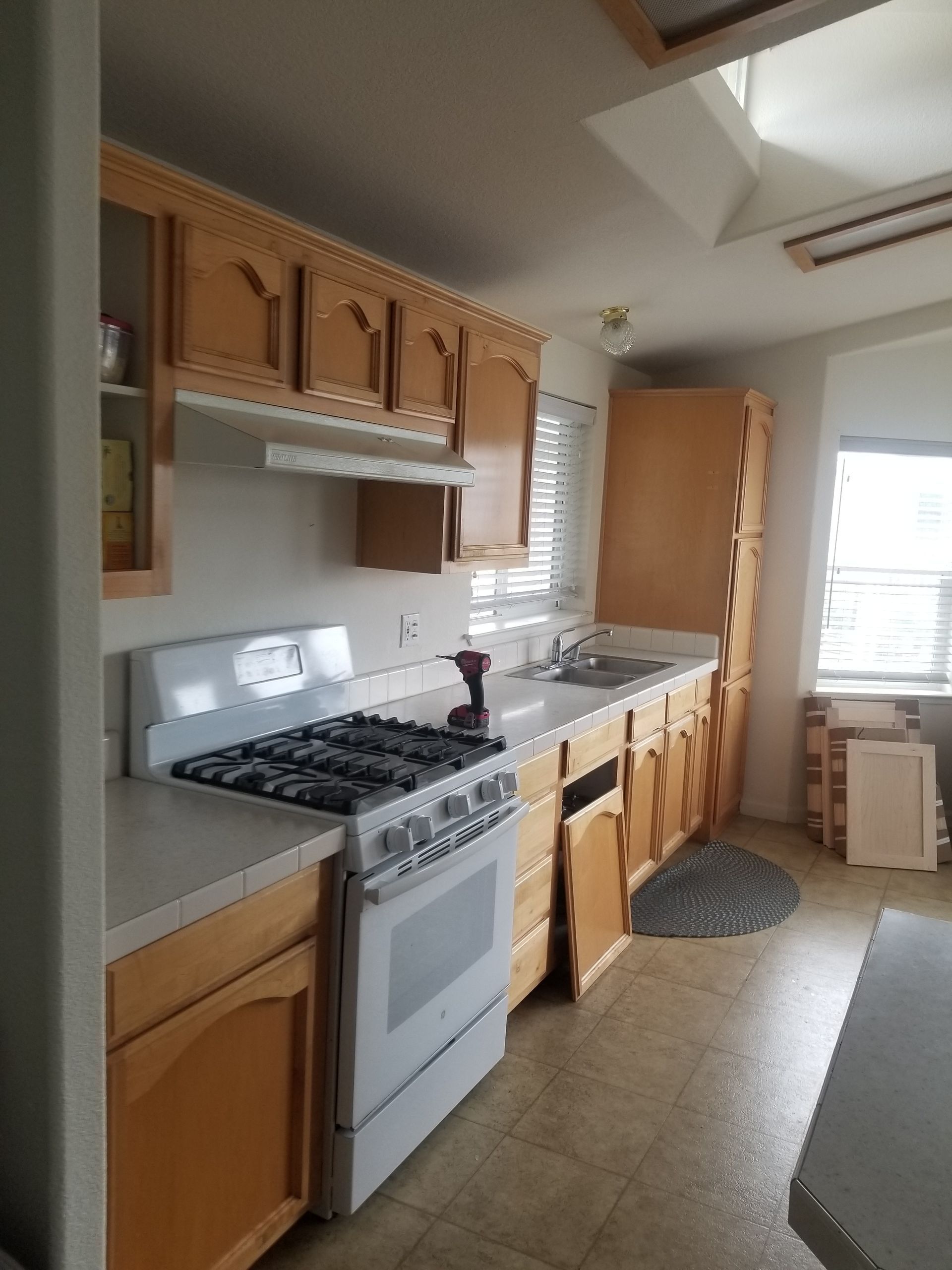 Kitchen with light wood cabinets, white appliances, and a window.