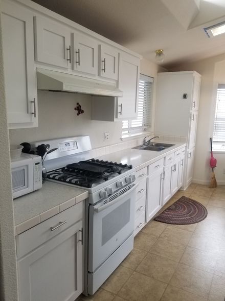 Kitchen with white cabinets, stainless steel appliances, and a wood island.