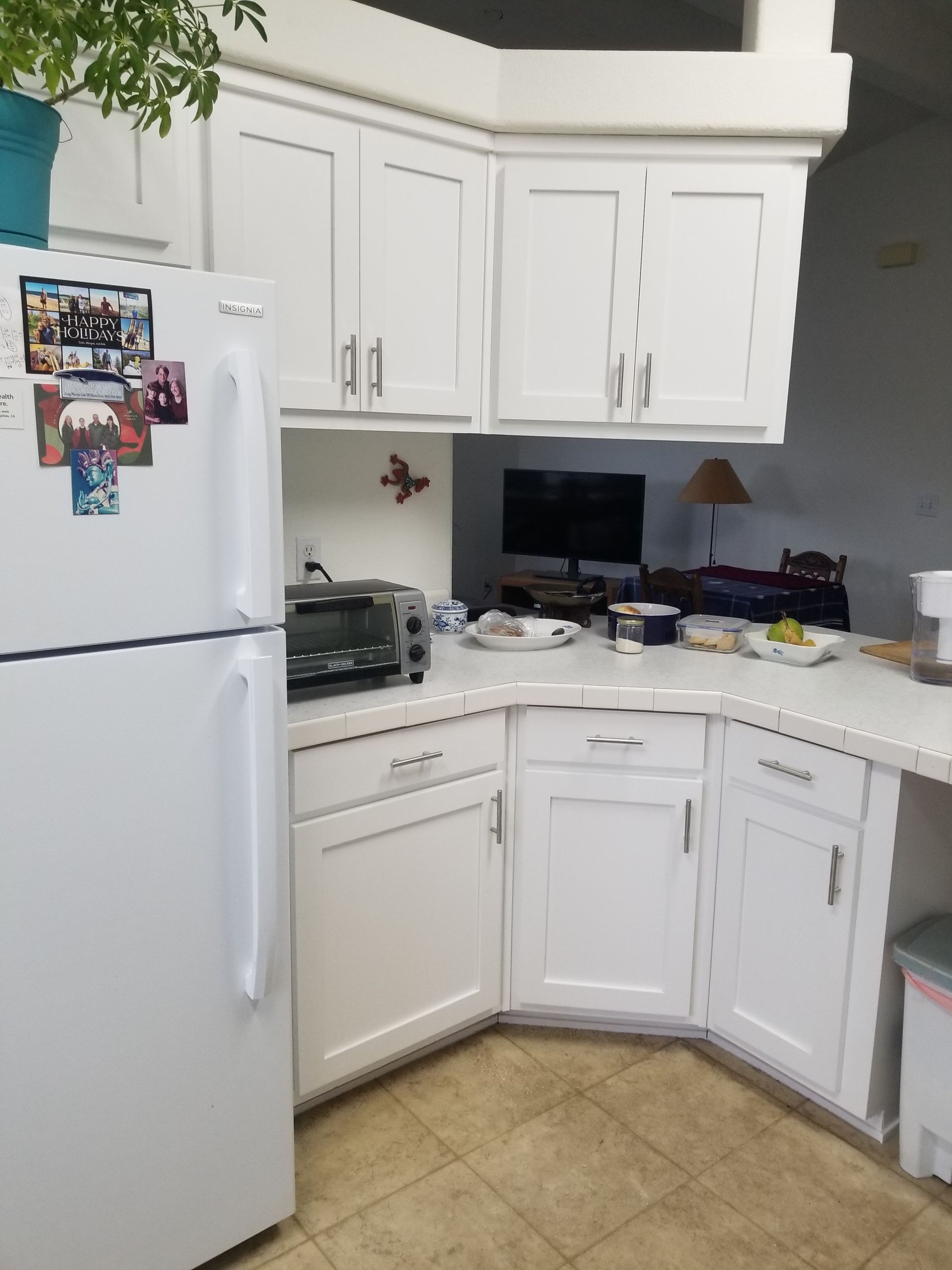 White kitchen cabinets and appliances. Refrigerator, toaster oven, and workspace.