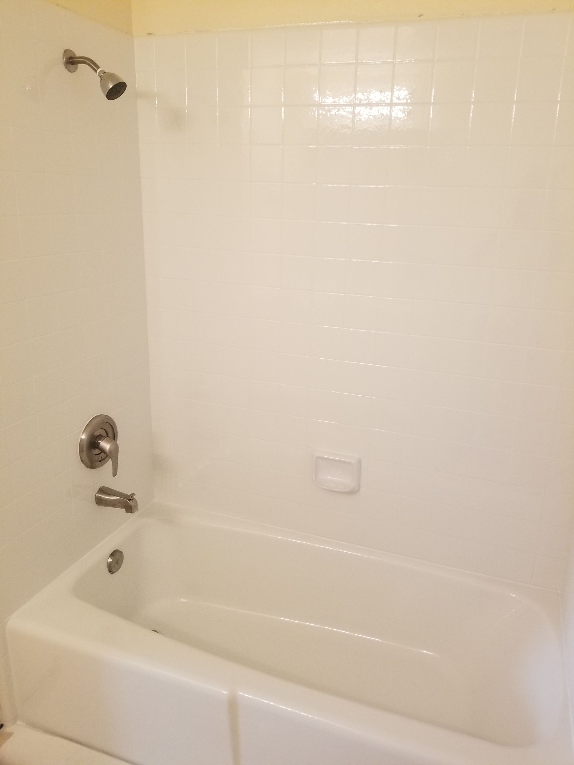 White bathtub and tiled shower stall with silver fixtures.