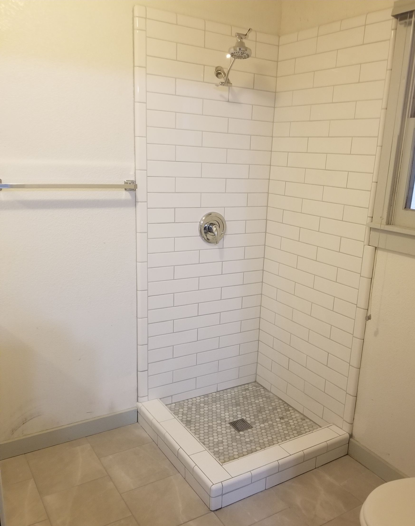 White bathroom with tub, toilet, double sink, and window with a blind.