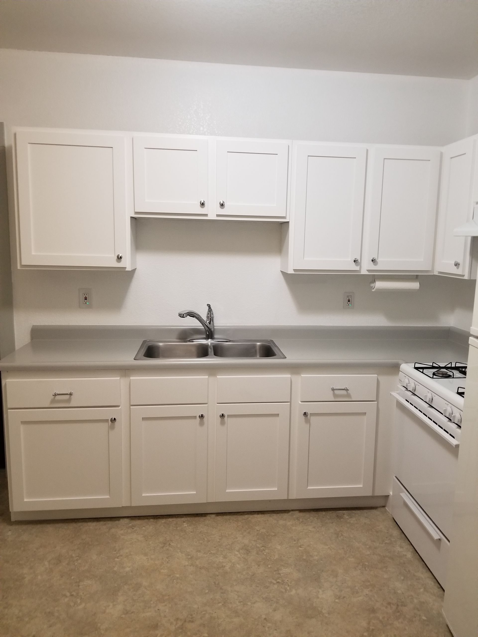 A kitchen with light gray cabinets, a built-in oven, and a skylight.