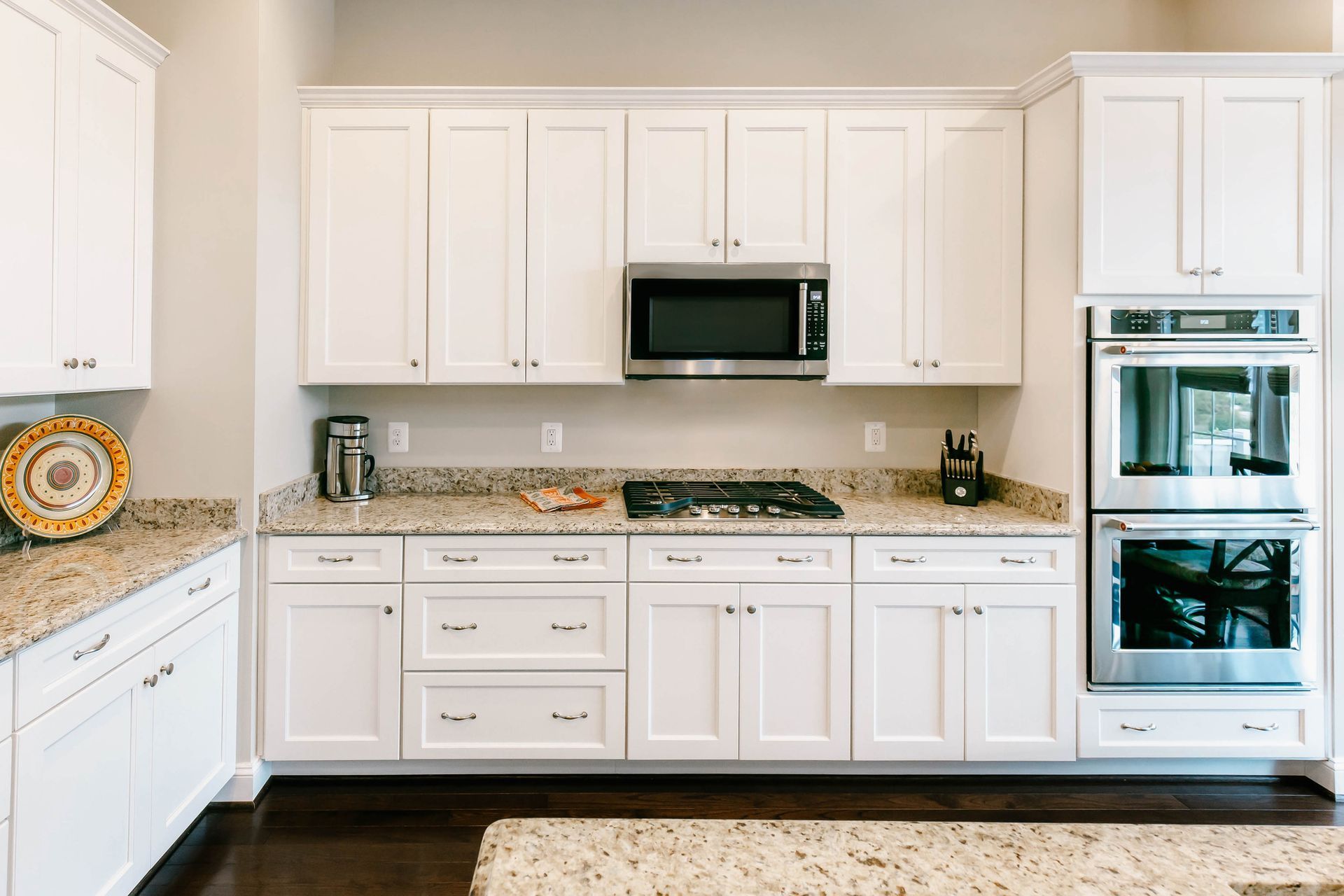 White kitchen cabinets with granite countertops and stainless steel appliances.