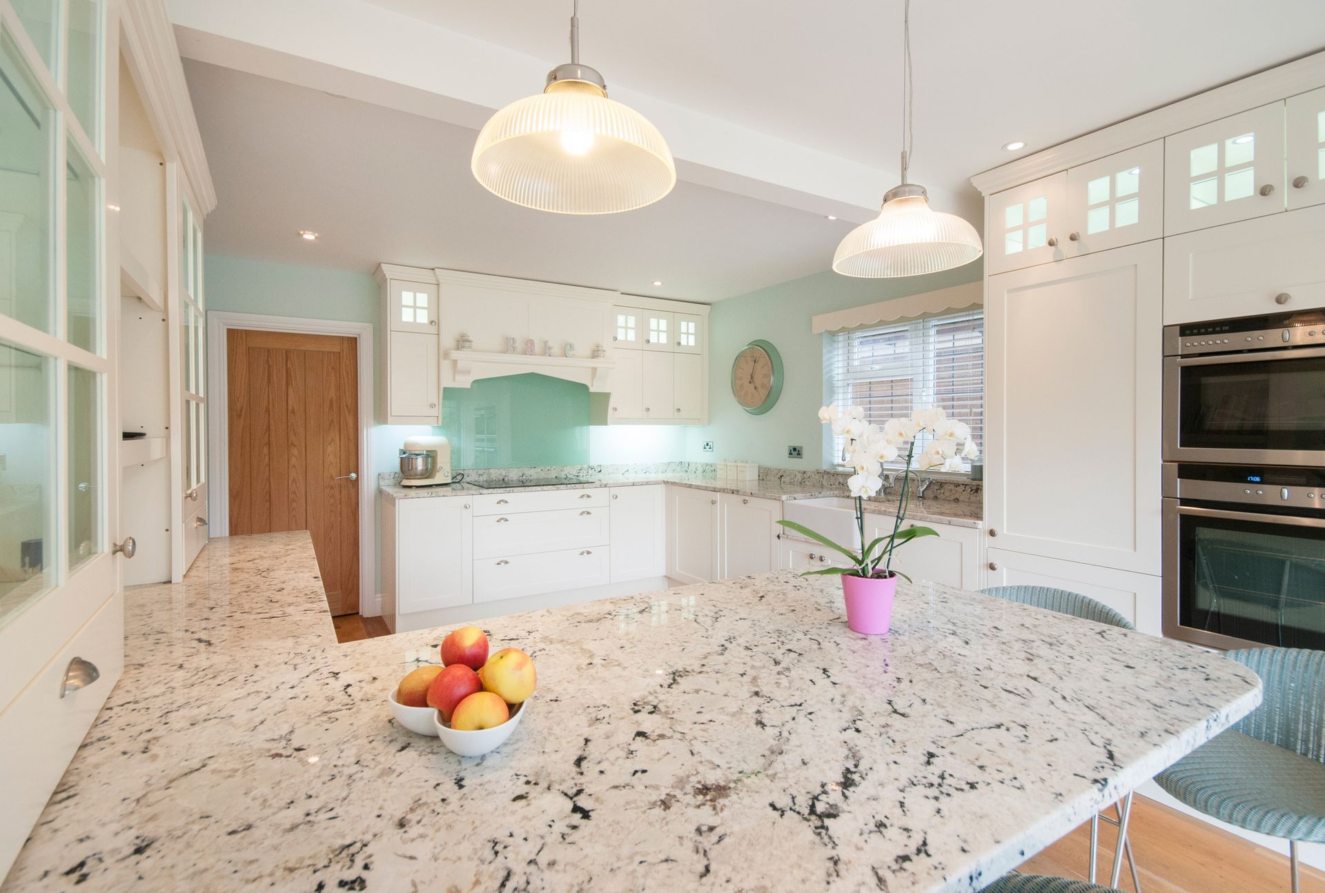 Bright kitchen with white cabinets, granite countertop, and two pendant lights.
