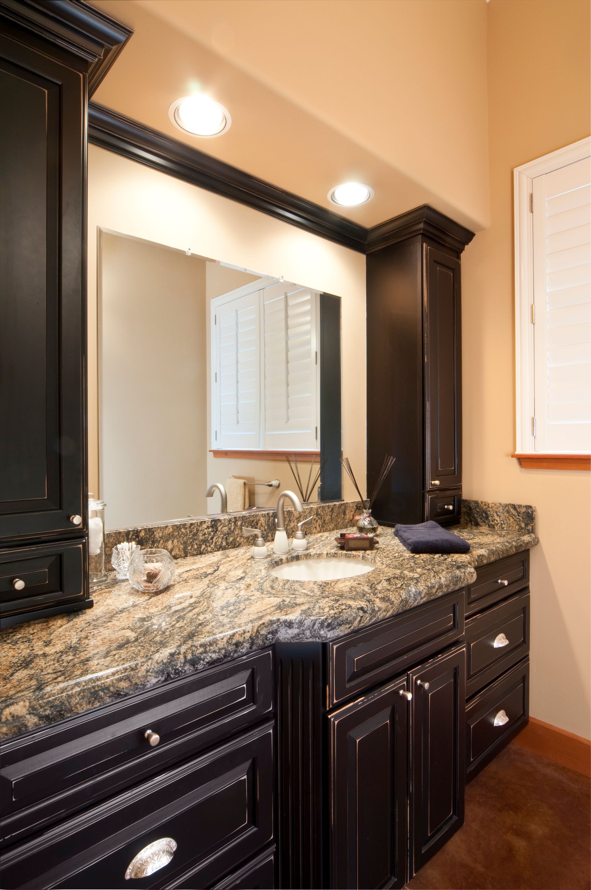 Dark wood bathroom vanity with granite countertop, mirror, and cabinet.