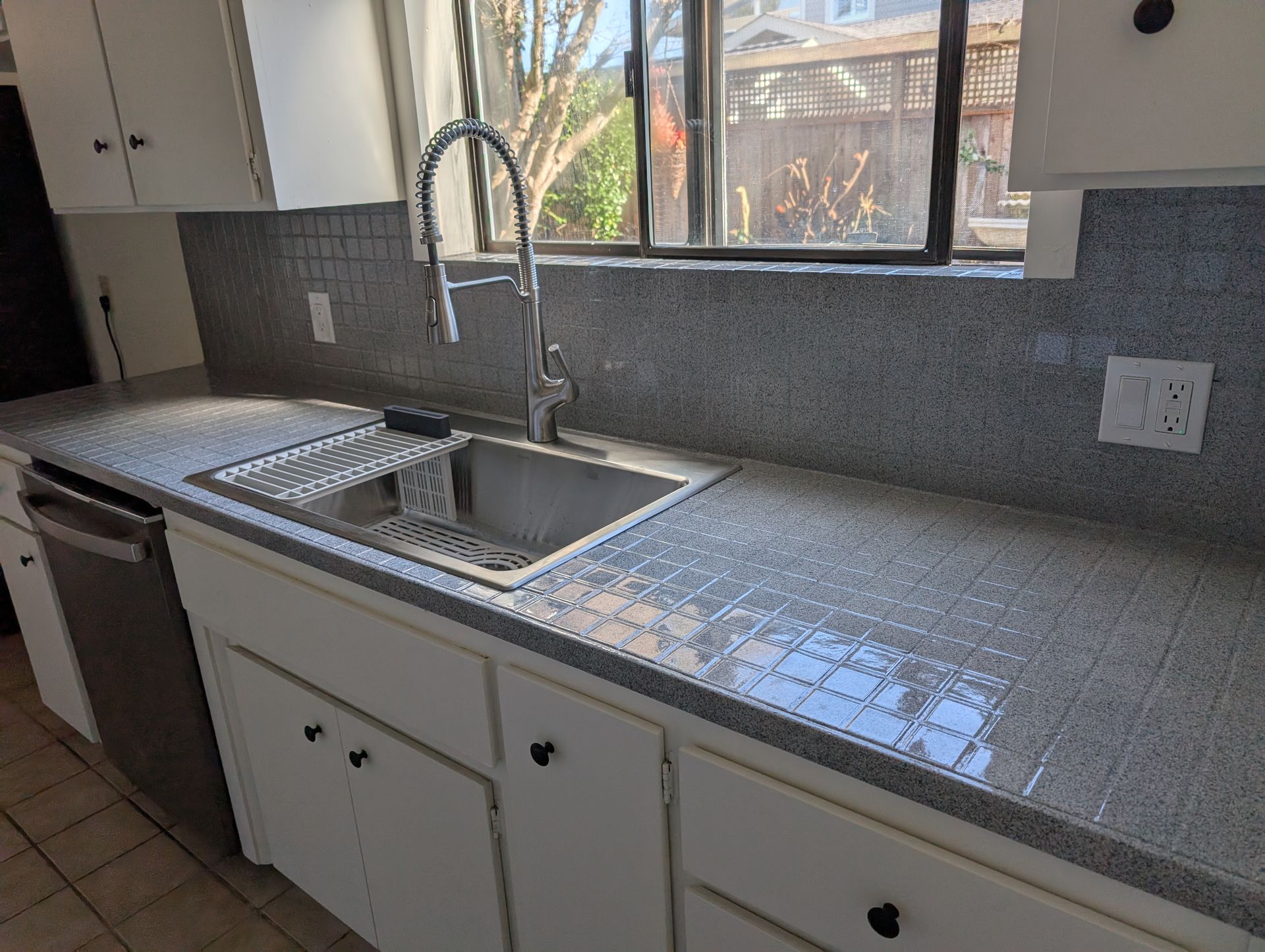 Modern white kitchen with island seating, stainless steel appliances, and wood floors.