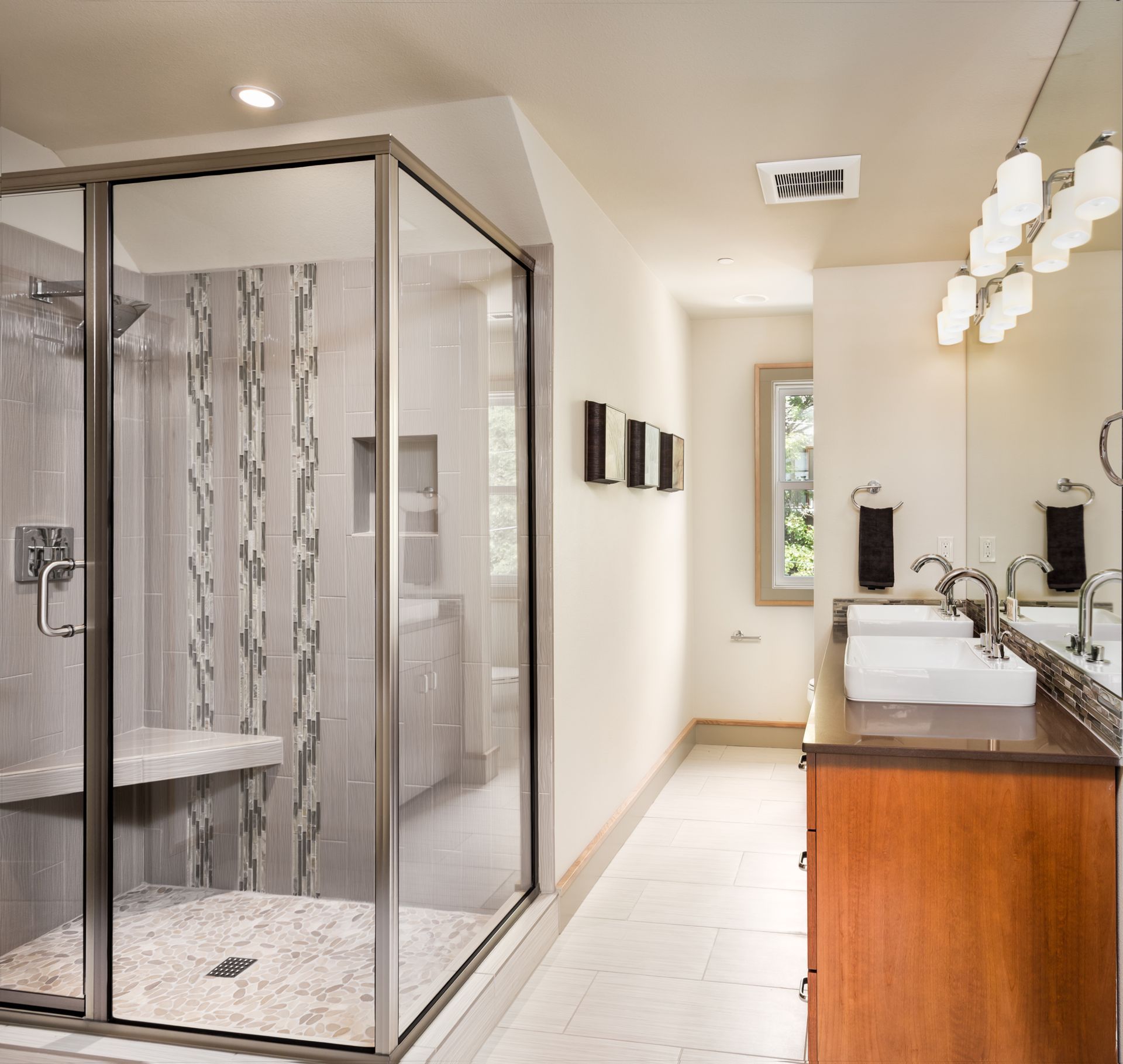 Modern bathroom with glass shower, double sinks, and wood vanity.
