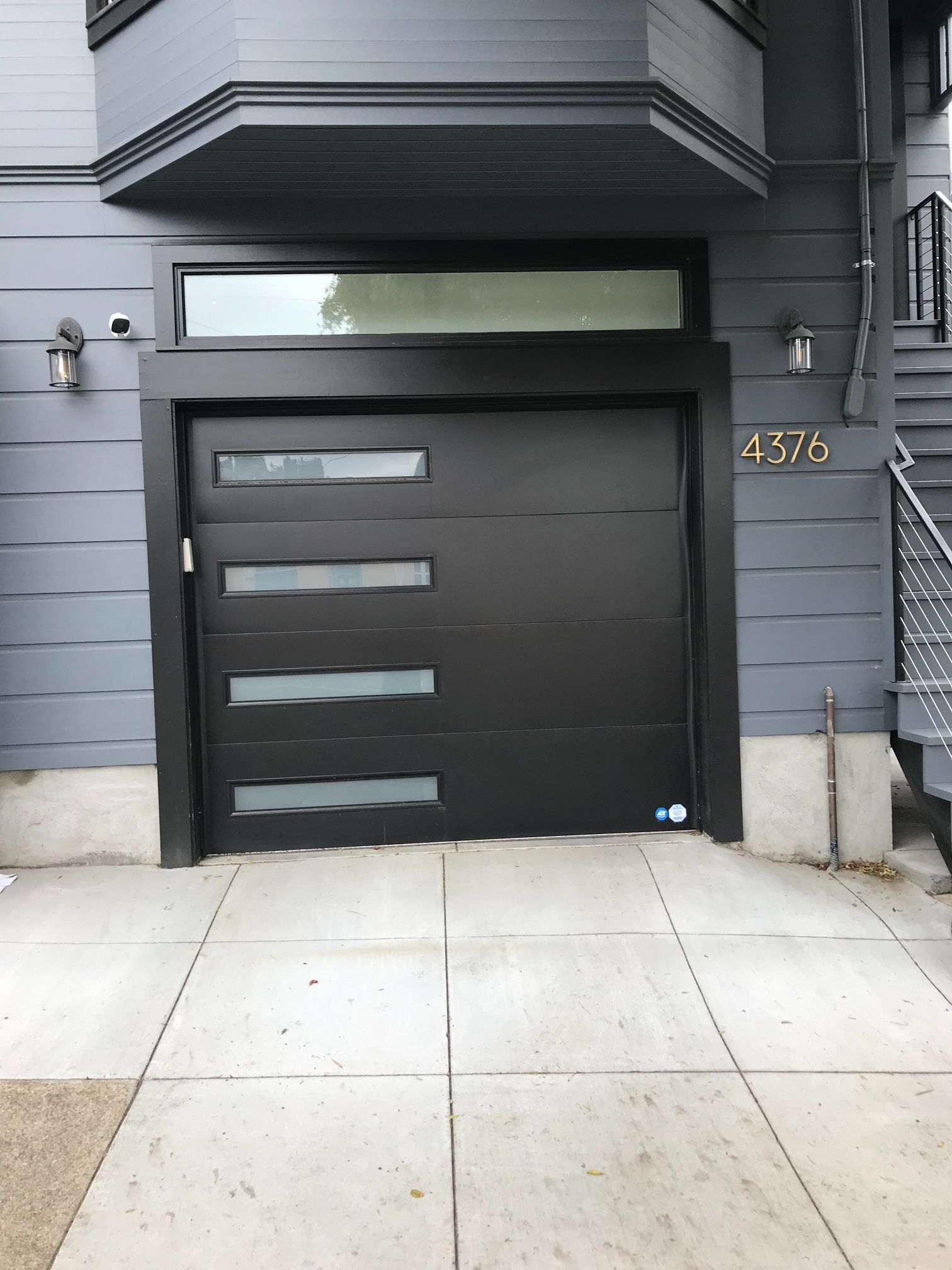 Modern gray townhouse garage door with narrow windows and house number 476 on the right side.