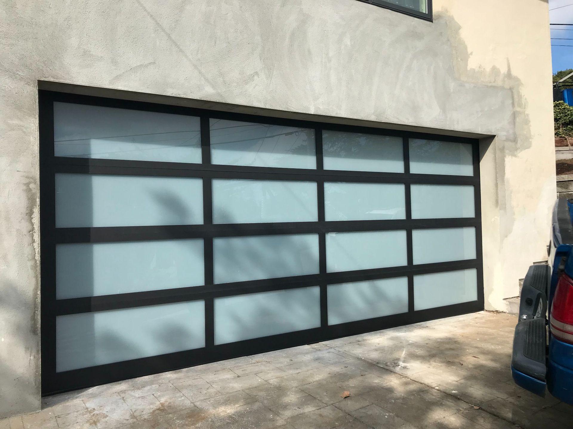 Black-framed frosted glass garage door on a light stucco building