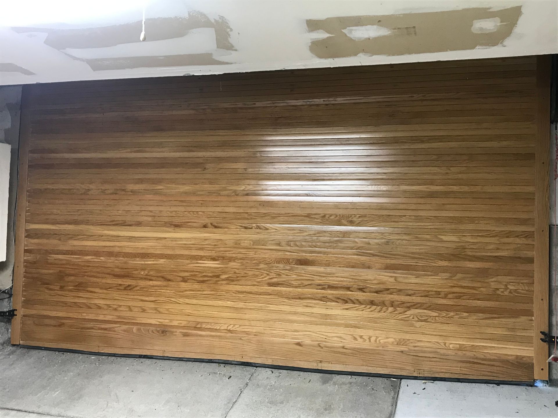 A wooden garage door is being installed in a garage.