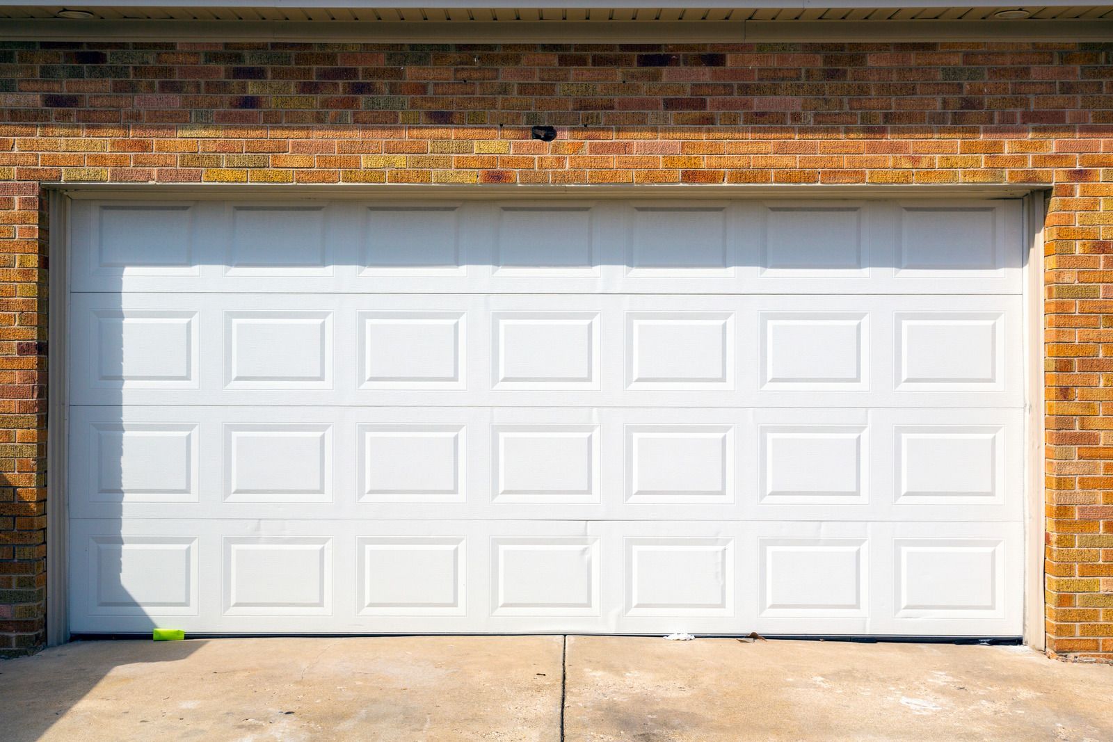 A white garage door is open on a brick building.