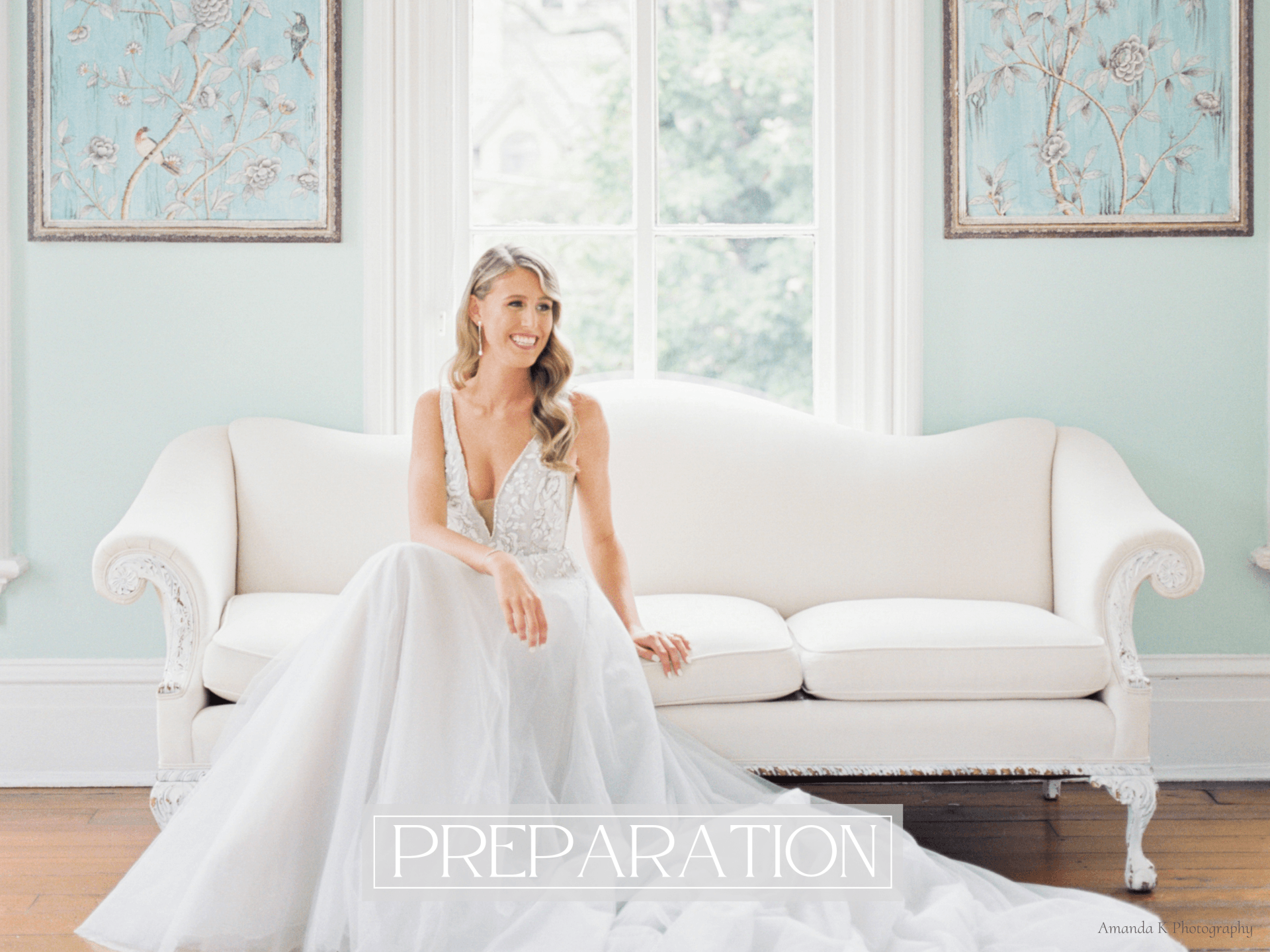 A bride in a wedding dress is sitting on a white couch smiling to her right.