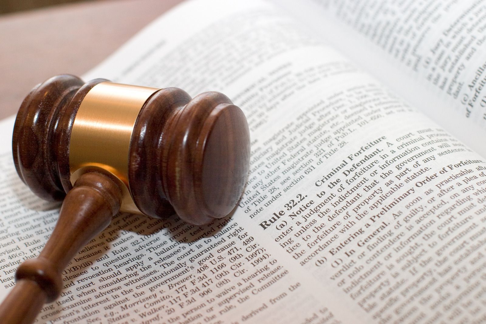 A wooden judge 's gavel is sitting on top of an open book