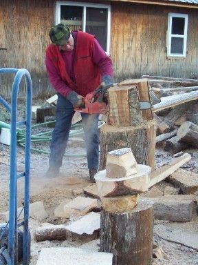 Sam Sanderson cutting wood with a chainsaw in front of a house.