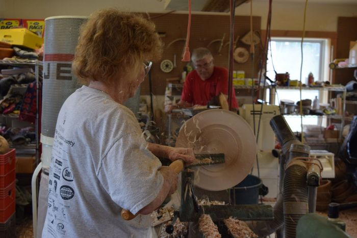 Weeza Sanderson using a lathe to hand turn a piece of wood into a beautiful wooden bowl in VT.