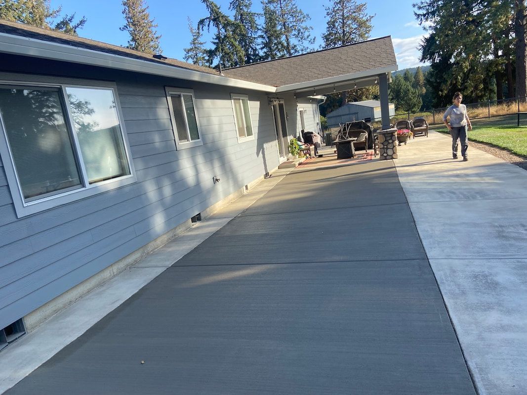 A man is standing on a concrete driveway in front of a house.