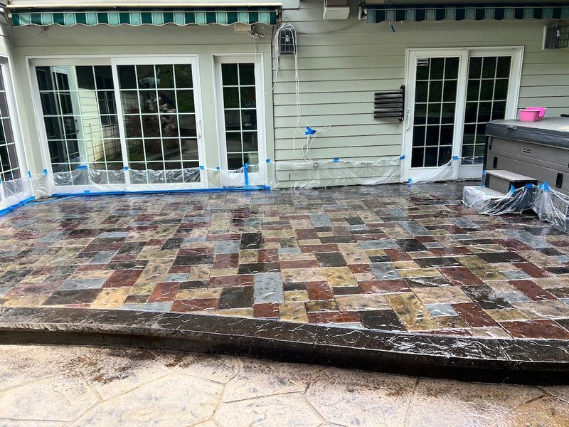A patio with a hot tub in the background and a house in the background.