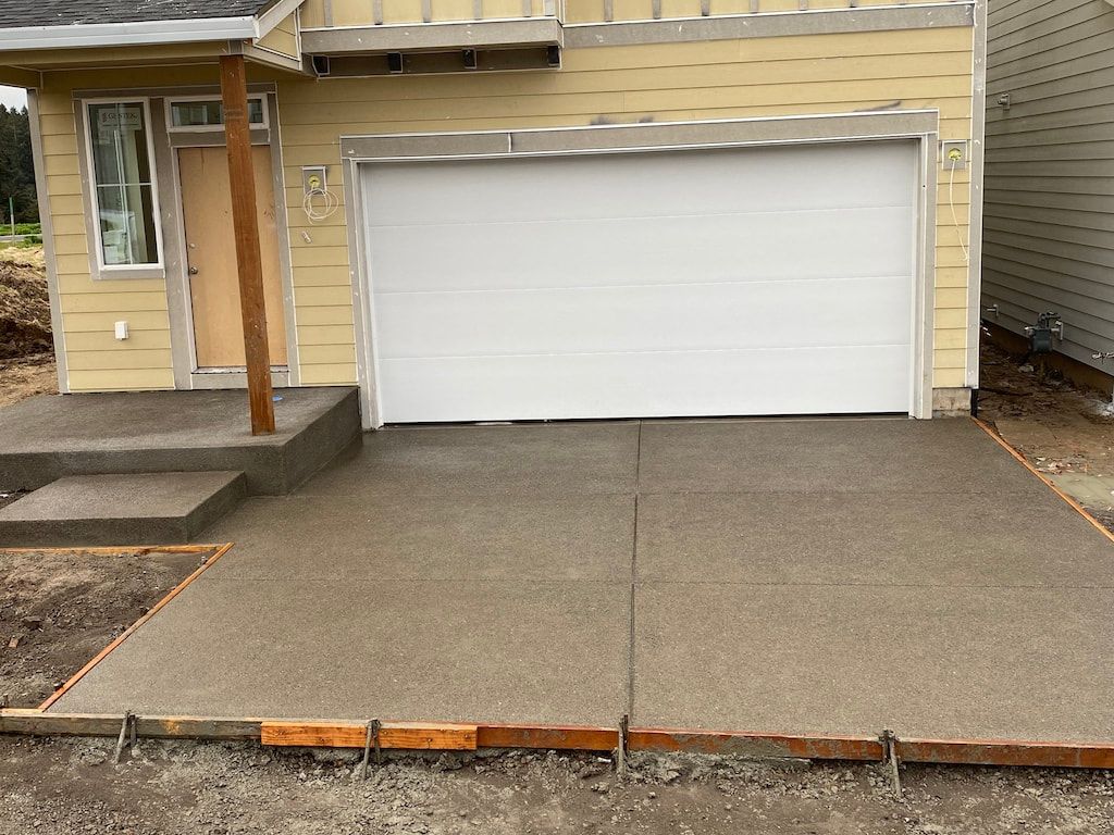 A yellow house with a white garage door and a concrete driveway in front of it.