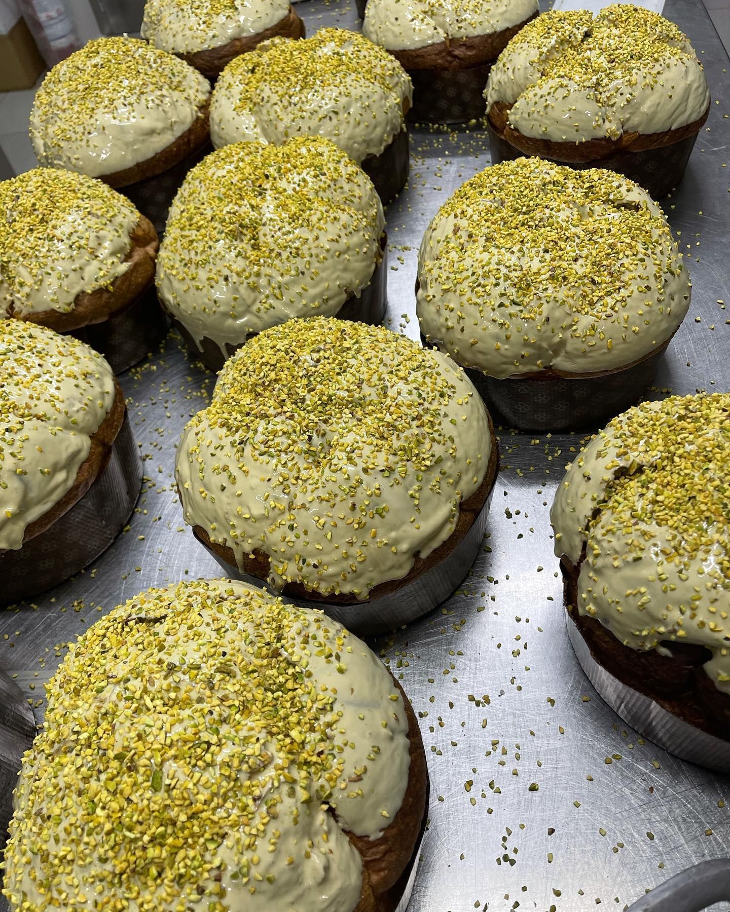 Primo piano di pagnotte di pane appena sfornate, rotonde, ricoperte di glassa cremosa e cosparse di granuli giallo-verdi.