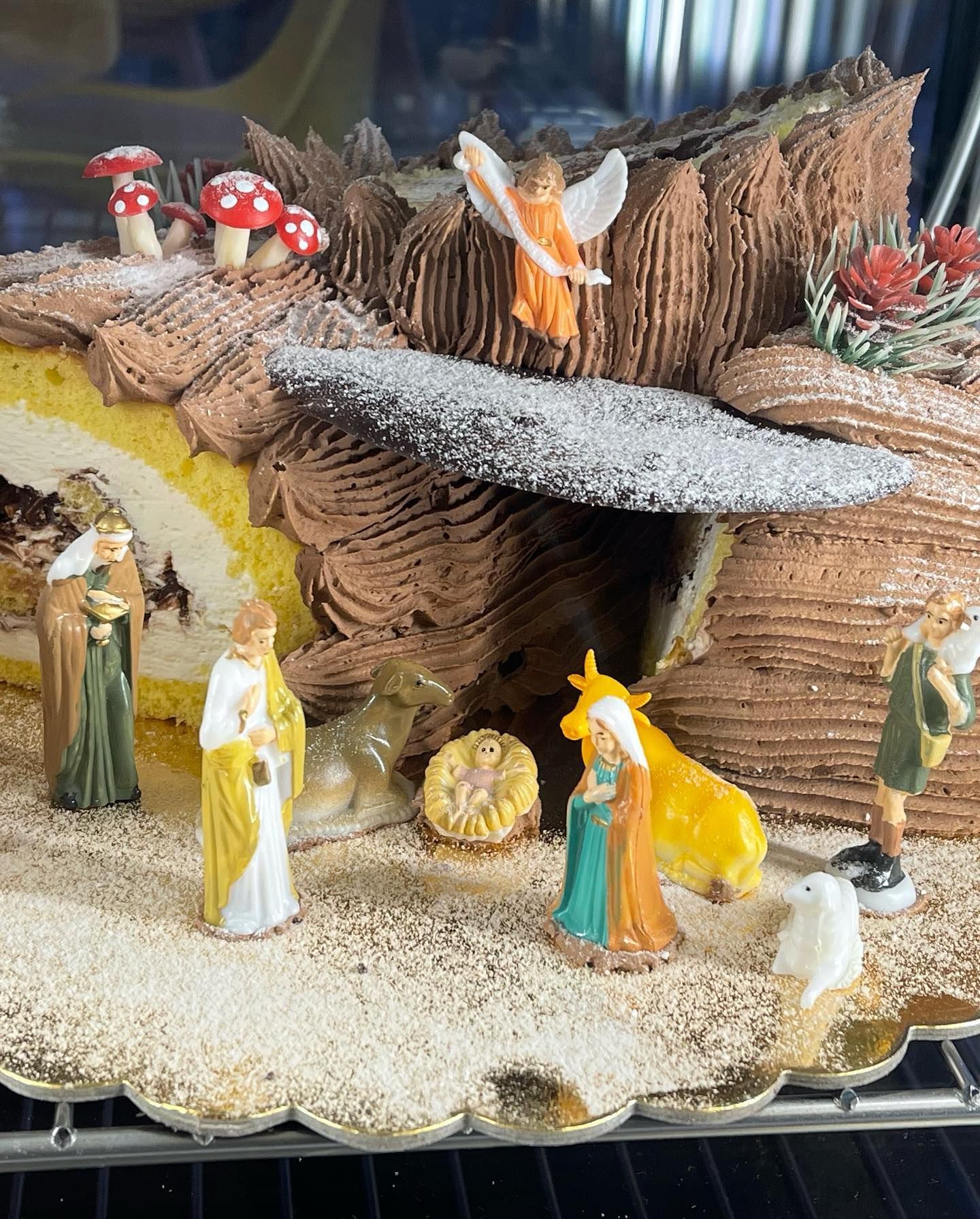 Tronchetto di Natale decorato con miniature di statuine del presepe e funghi.