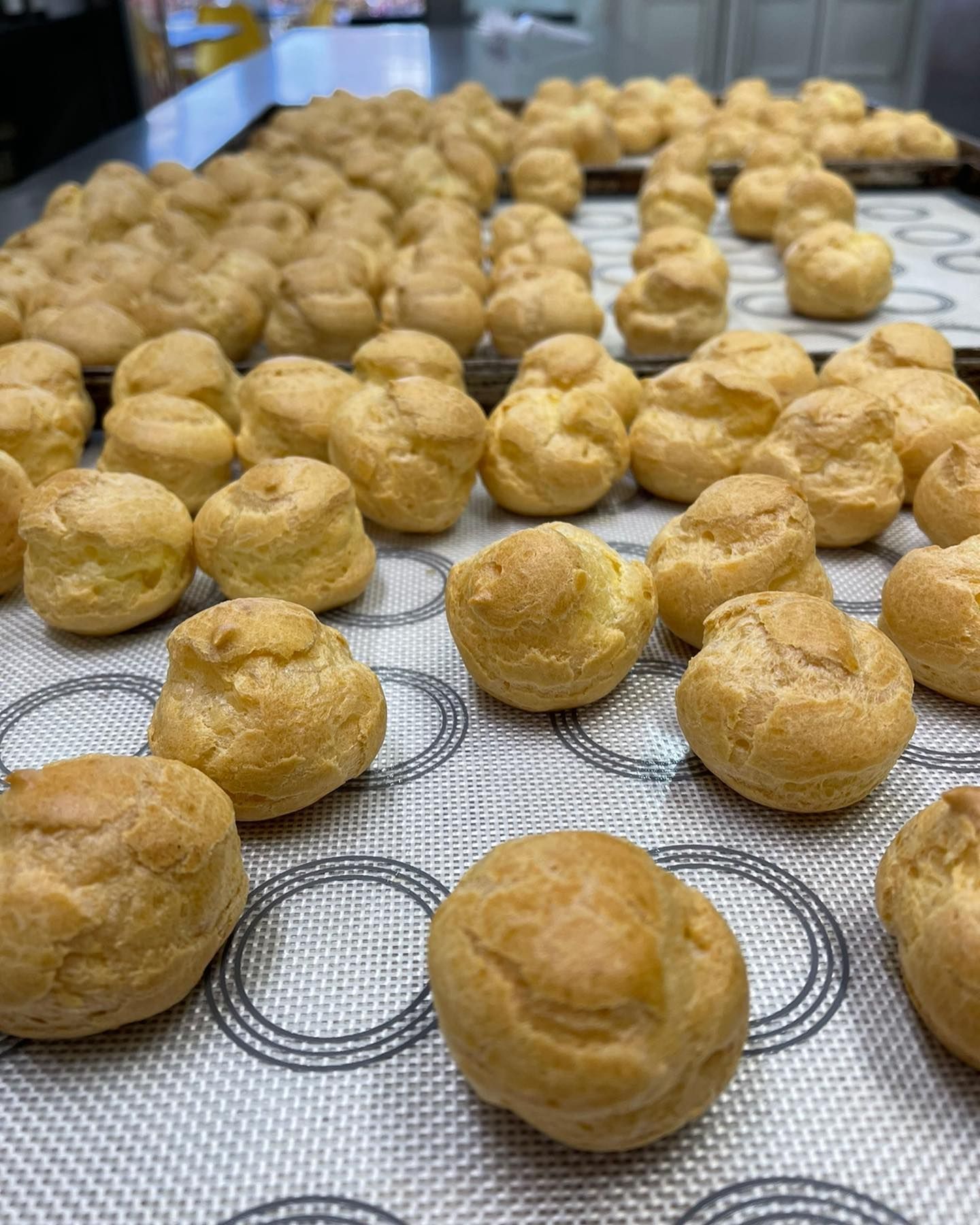 Bignè dorati disposti su un tappetino da forno in silicone in cucina.