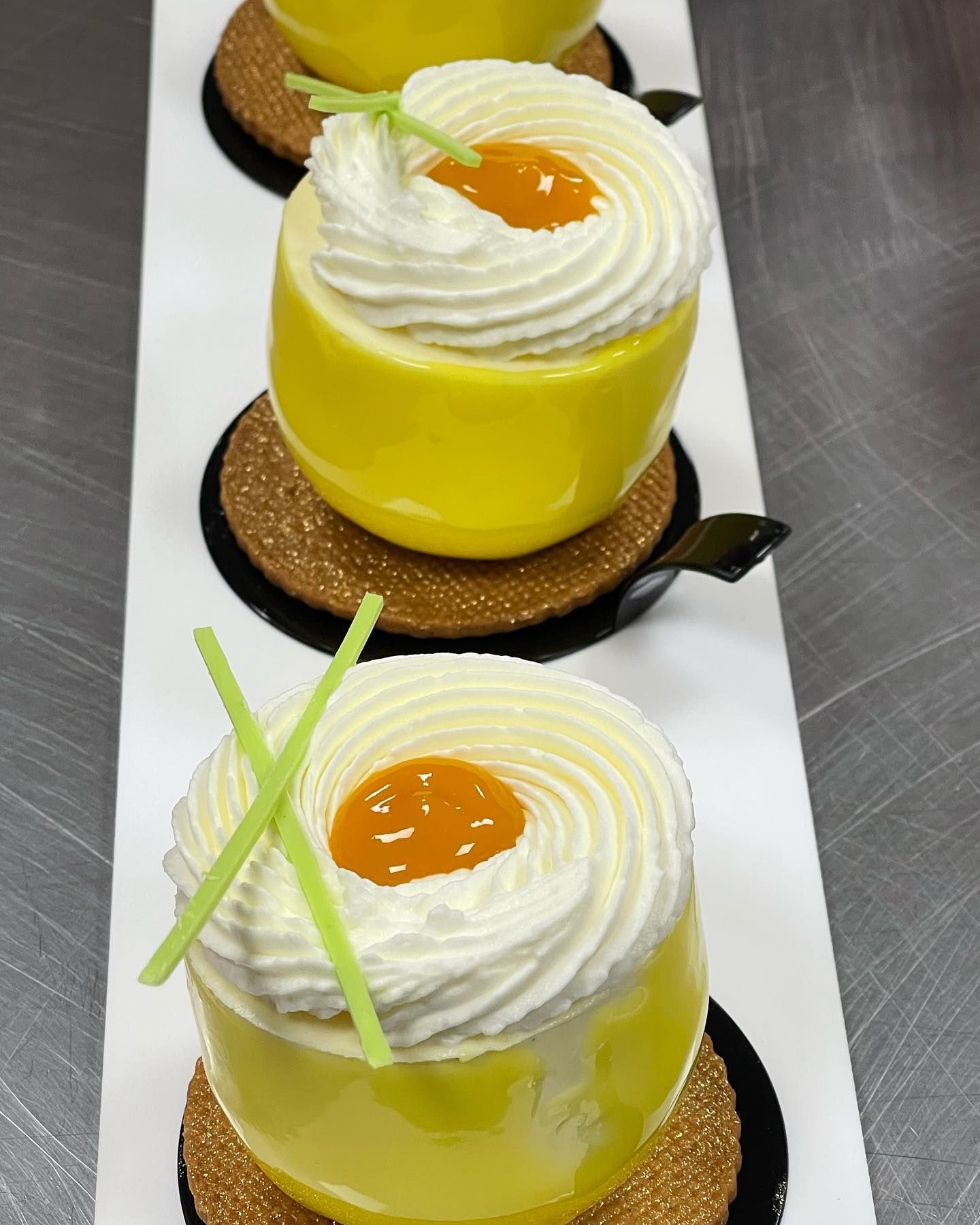 Dessert di mousse gialla con panna montata e guarnizione di agrumi su un piatto bianco.