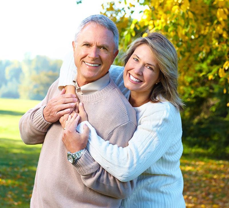 White elderly couple embracing each other at the park