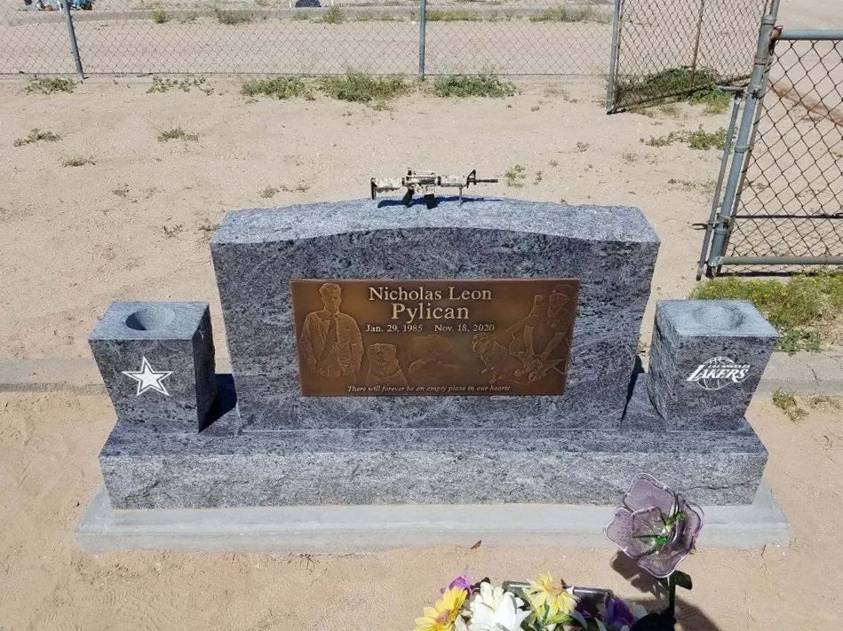 grey and bronze headstone with mini rifle on top and two vases with sports team engravings