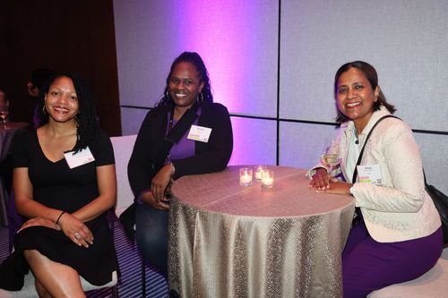Three women smiling while seated around a table.