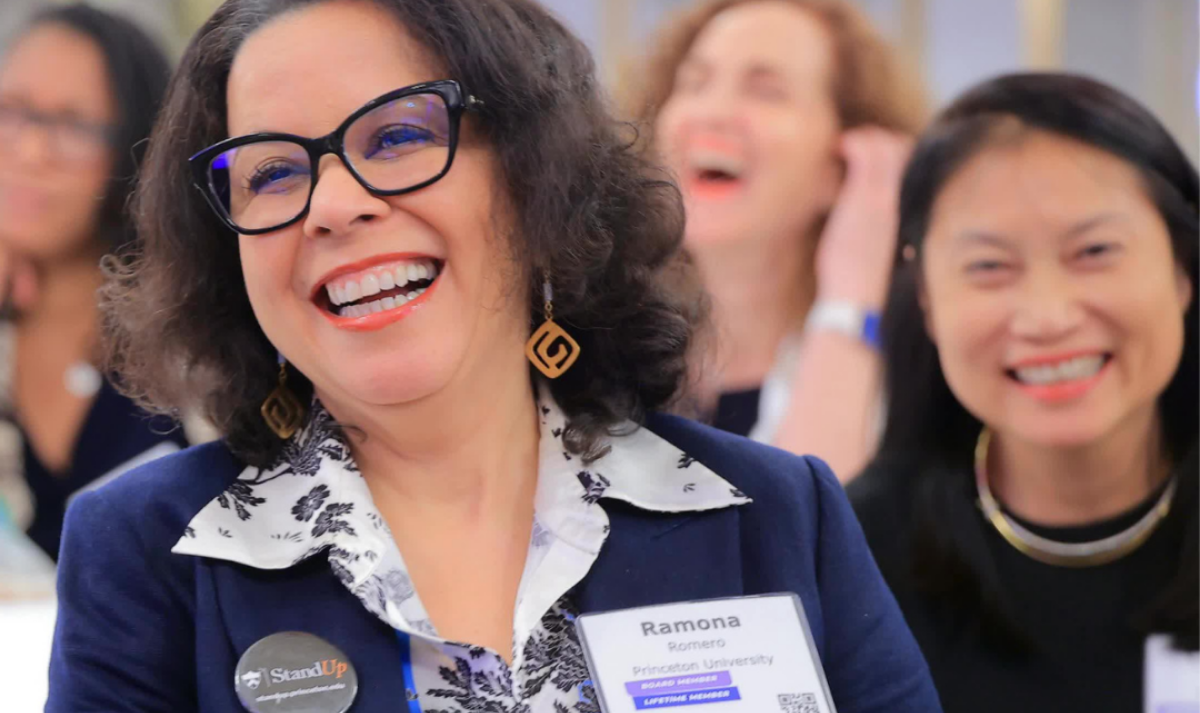 Three women smiling while seated around a table.
