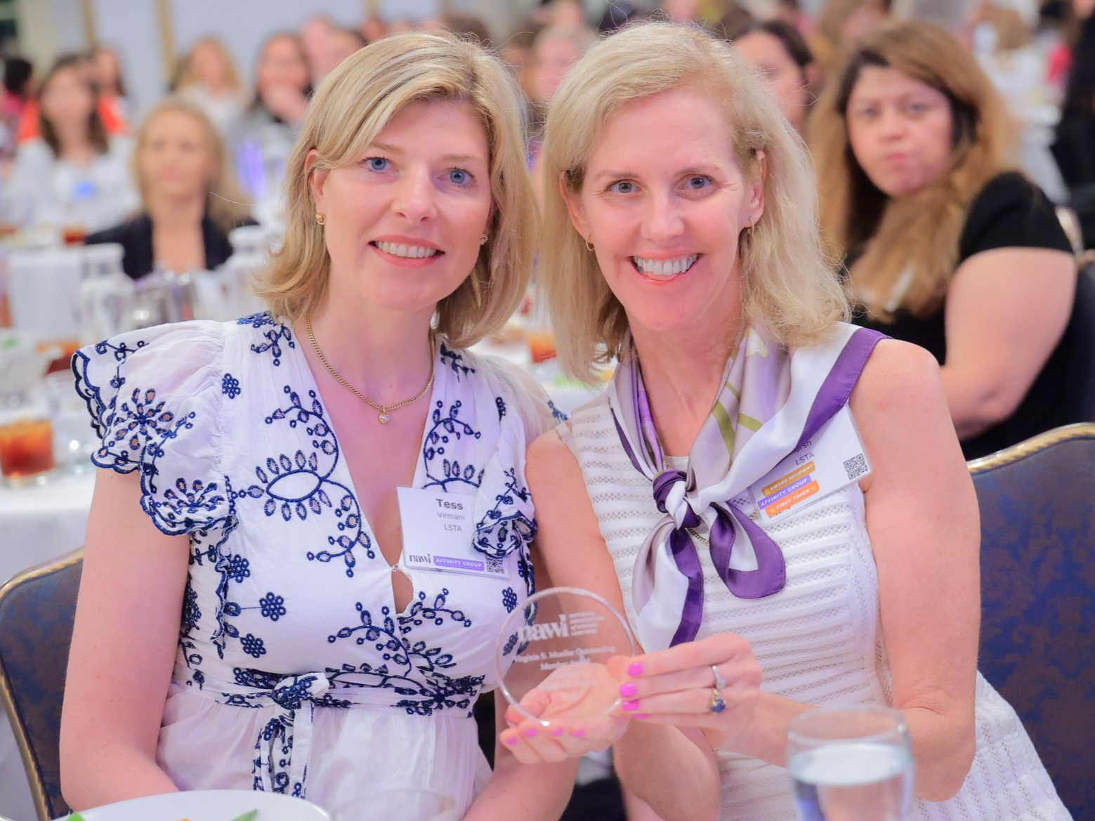 Two members smiling and holding an award.