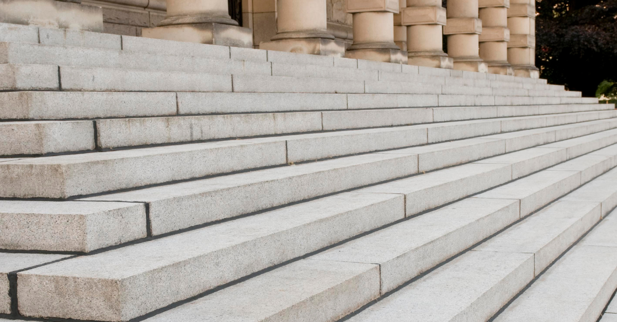 Stone steps leading up to a building with columns, in natural light.