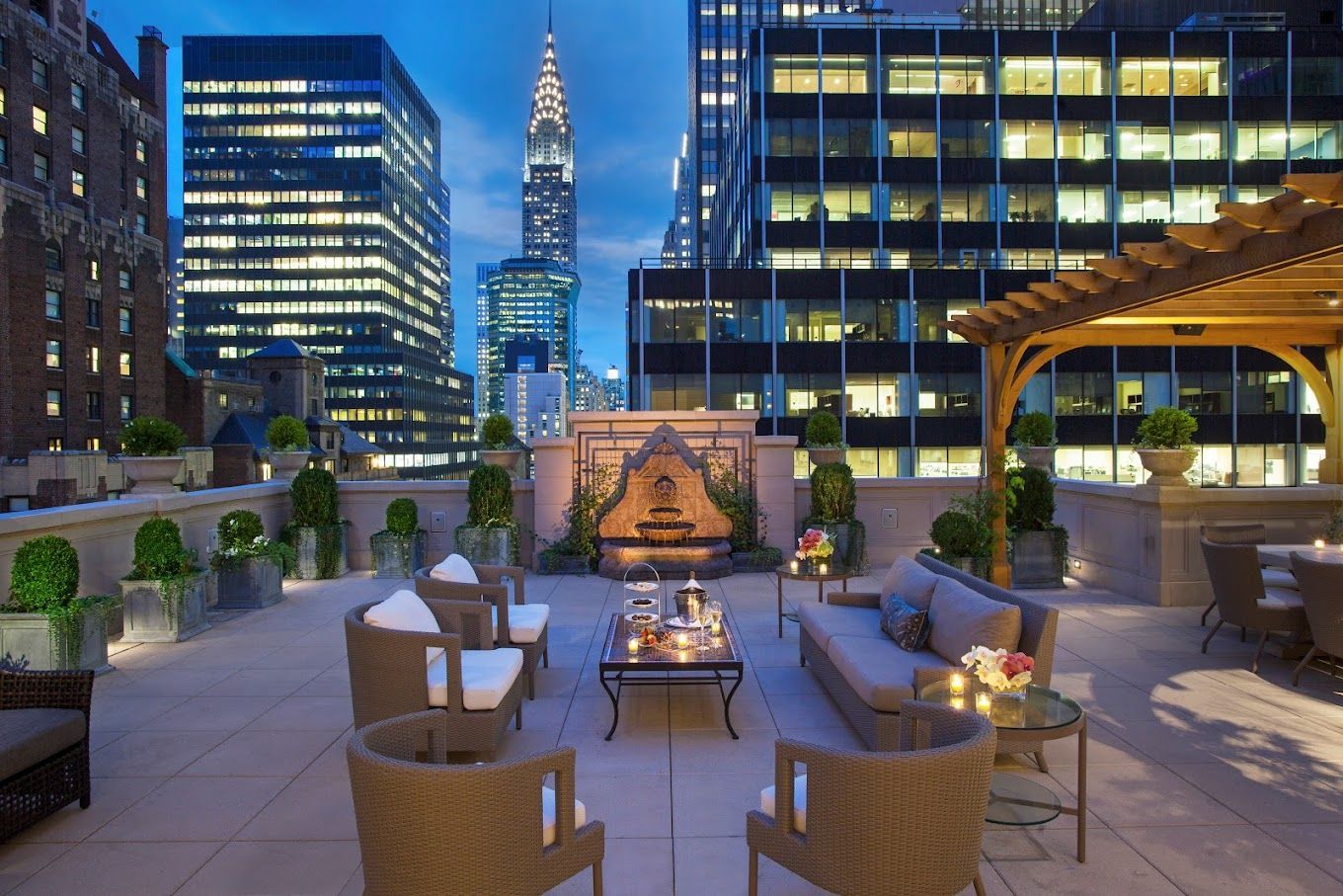 A rooftop lounge area in a city with skyscrapers at night.