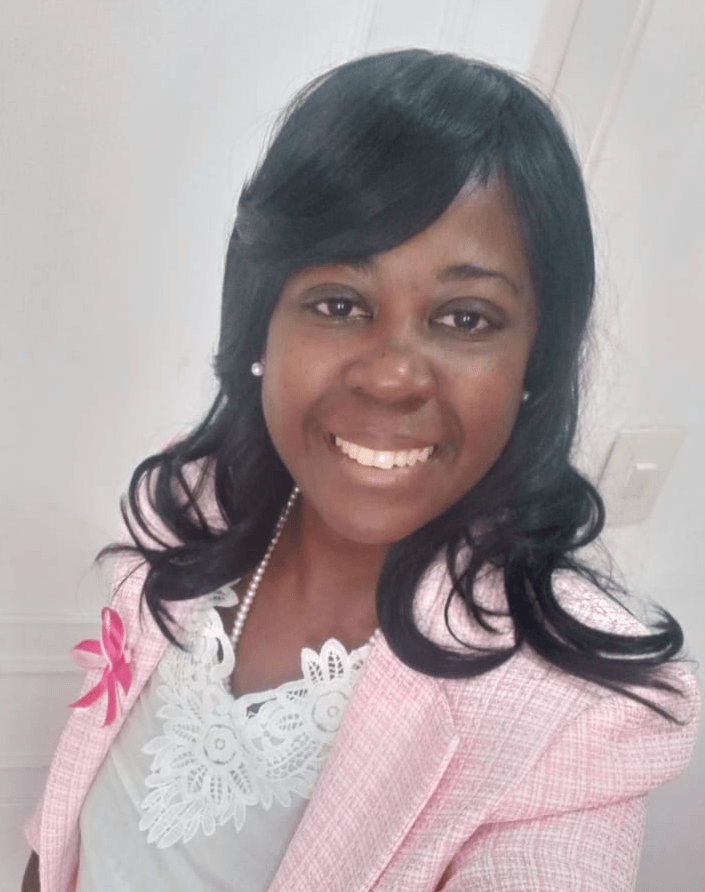 Uma mulher está vestindo uma jaqueta rosa e sorrindo para a câmera.