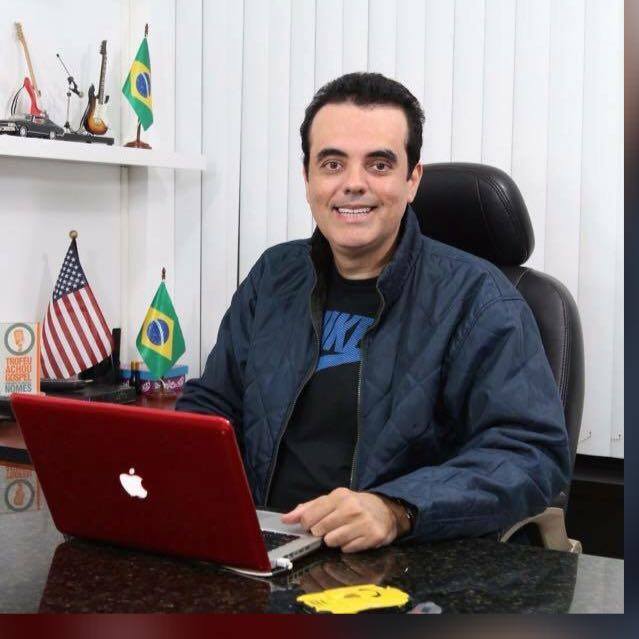 Um homem está sentado em uma mesa com um laptop da Apple