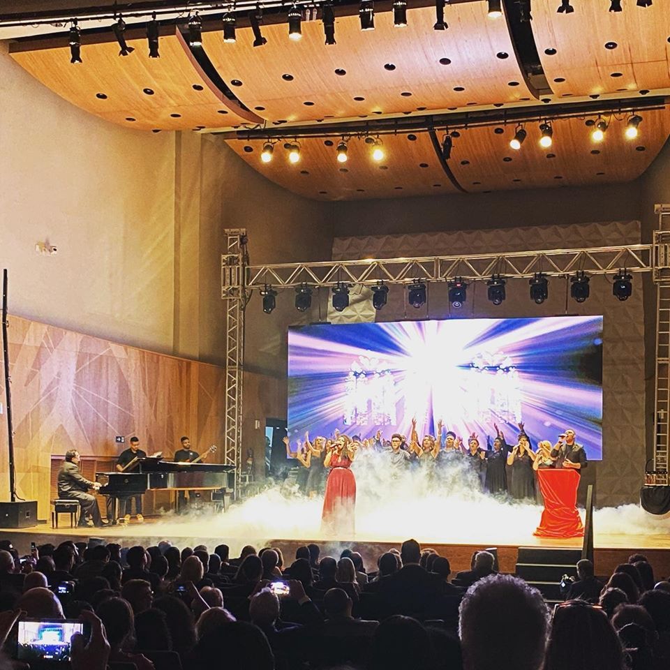 Um grupo de pessoas em pé em um palco em frente a uma tela grande