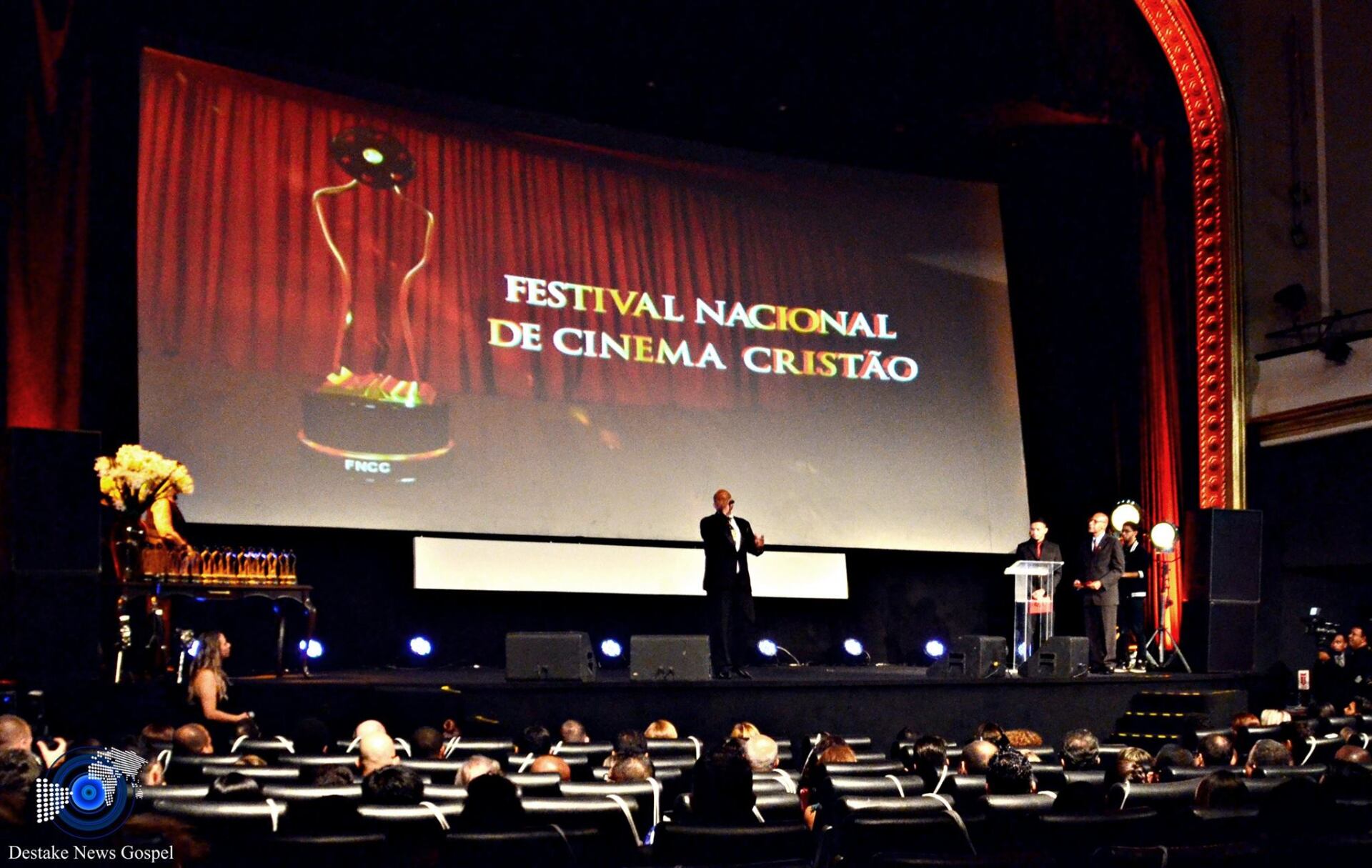Um homem está em frente a uma tela grande que diz festival nacional de cinema cristao